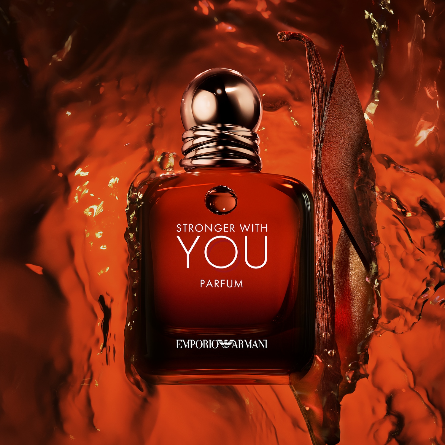 A Stronger With You Parfum üvegének közeli képe látható, melyet narancssárga háttér előtt, egy vaníliarúd és egy bőrdarab egészít ki.