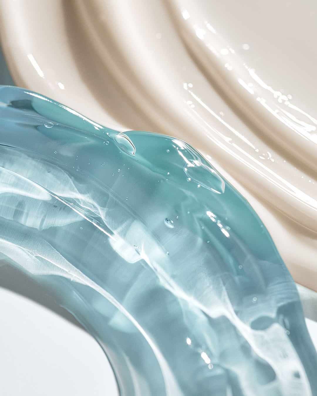 Šviesiai mėlynos ir kreminės spalvos kosmetikos priemonės tepinėliai sukuria gaivų ir prabangų pojūtį.