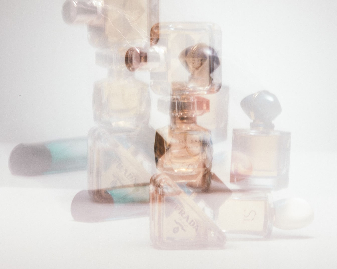 Mehrere Parfümflaschen von Marken wie Prada und Giorgio Armani stehen übereinander, wobei die klaren und goldenen Flakons einen luxuriösen Eindruck vermitteln.