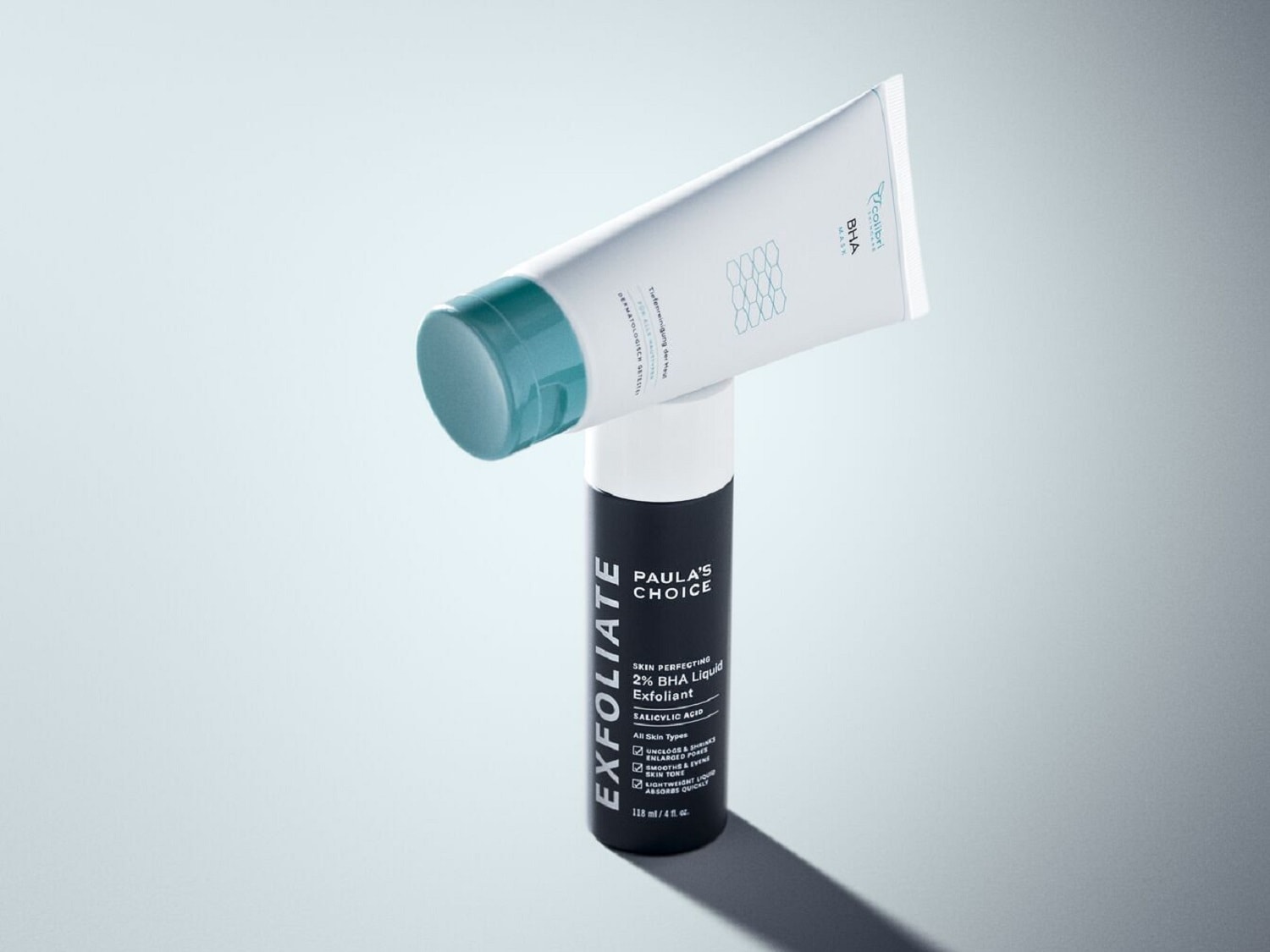 Auf dem Bild sind Paula's Choice 2% BHA Liquid Exfoliant in einer schwarzen Flasche und Colibri Skincare BHA Maske in einer weißen Tube zu sehen.