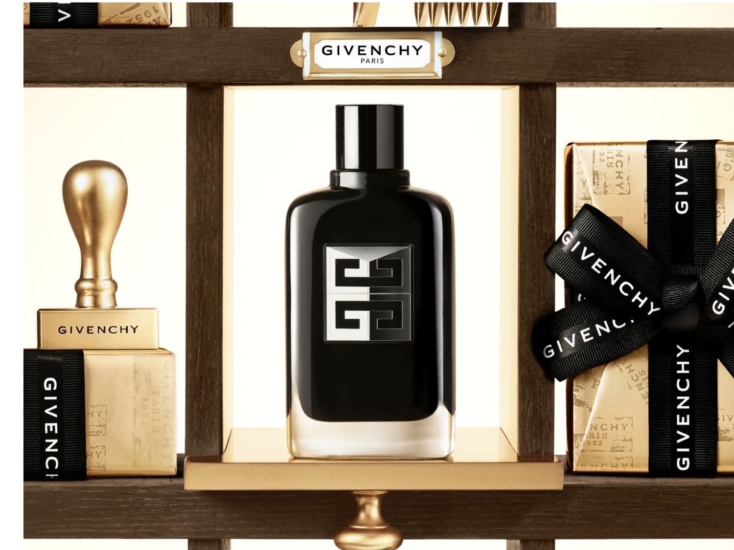 Der Givenchy Gentleman Eau de Parfum Flakon ist in einem eleganten schwarzen Design mit einem silbernen Logo gehalten und steht auf einem goldenen Regal, umgeben von luxuriösen Geschenkboxen.