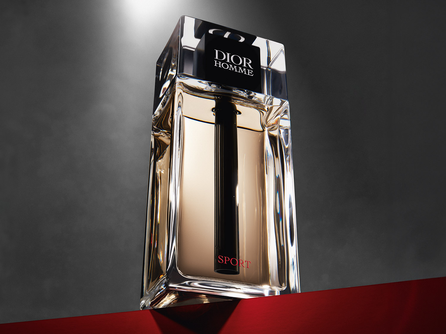 Ein Dior Homme Sport Parfümflakon mit klarem Glas und schwarzer Aufschrift steht auf einer roten Oberfläche vor einem grauen Hintergrund.