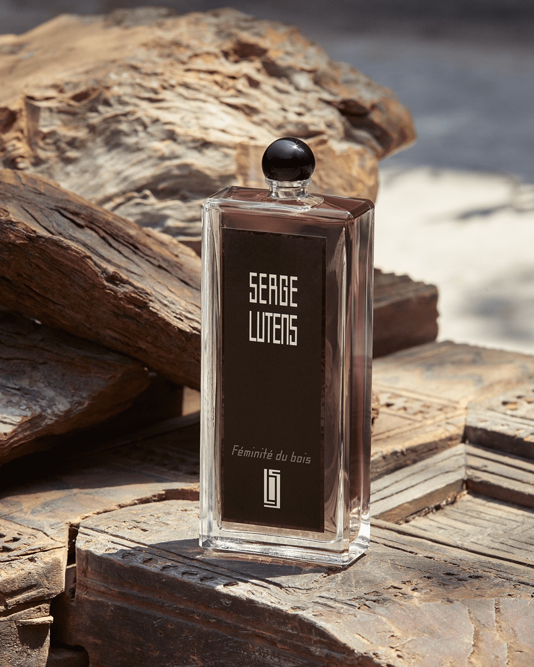 Découvrez Féminité du Bois de Serge Lutens, un parfum ambré boisé présenté dans un flacon en verre transparent avec un bouchon noir, évoquant l'élégance et la sophistication.