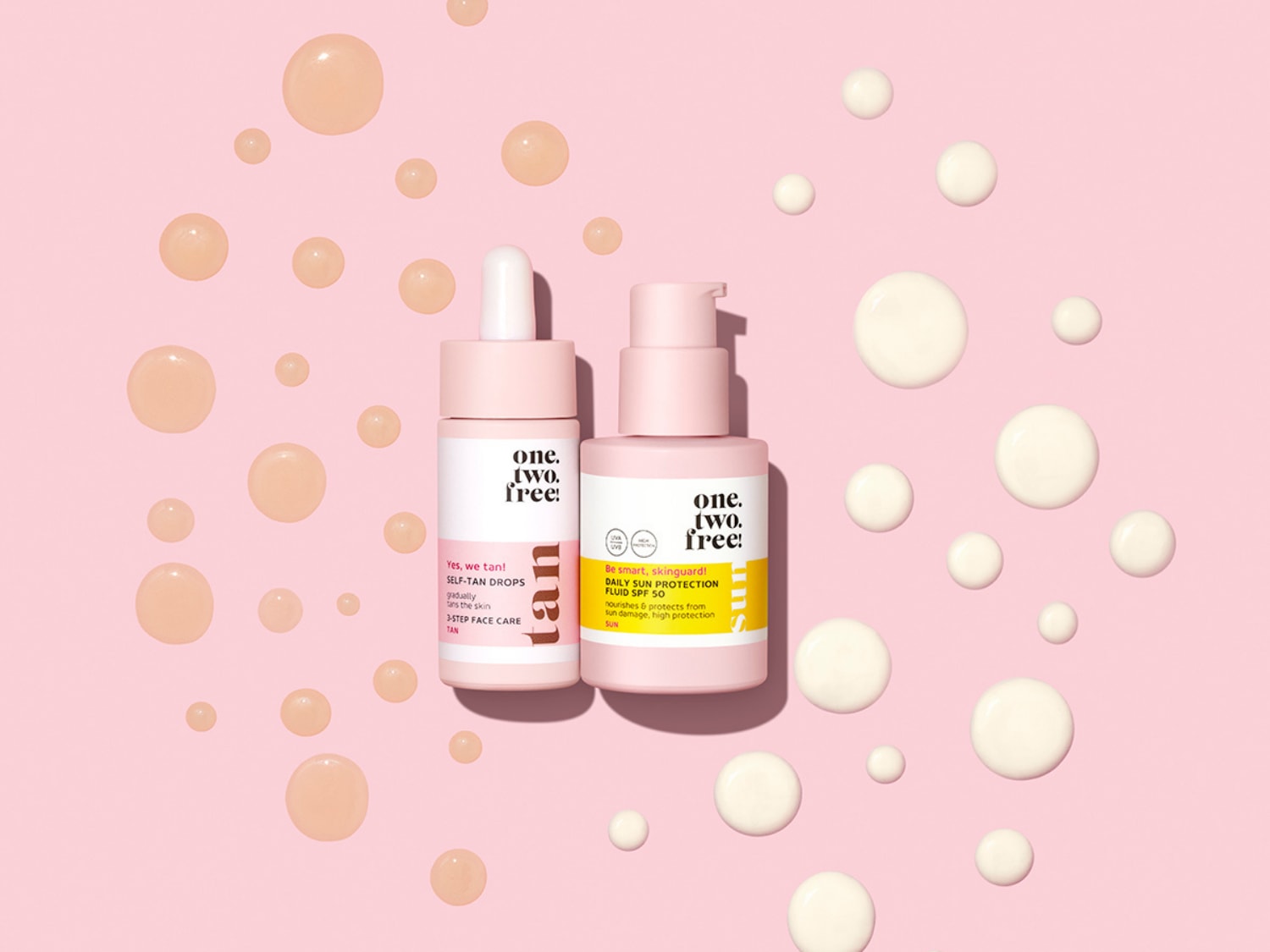 Švelniai rožiniame fone pavaizduoti du „one.two.free!“ odos priežiūros buteliukai: „Self-Tan Drops“, palaipsniui įdeginantys odą, ir „Daily Sun Protection Fluid SPF 50“, maitinantis ir apsaugantis nuo saulės žalos.