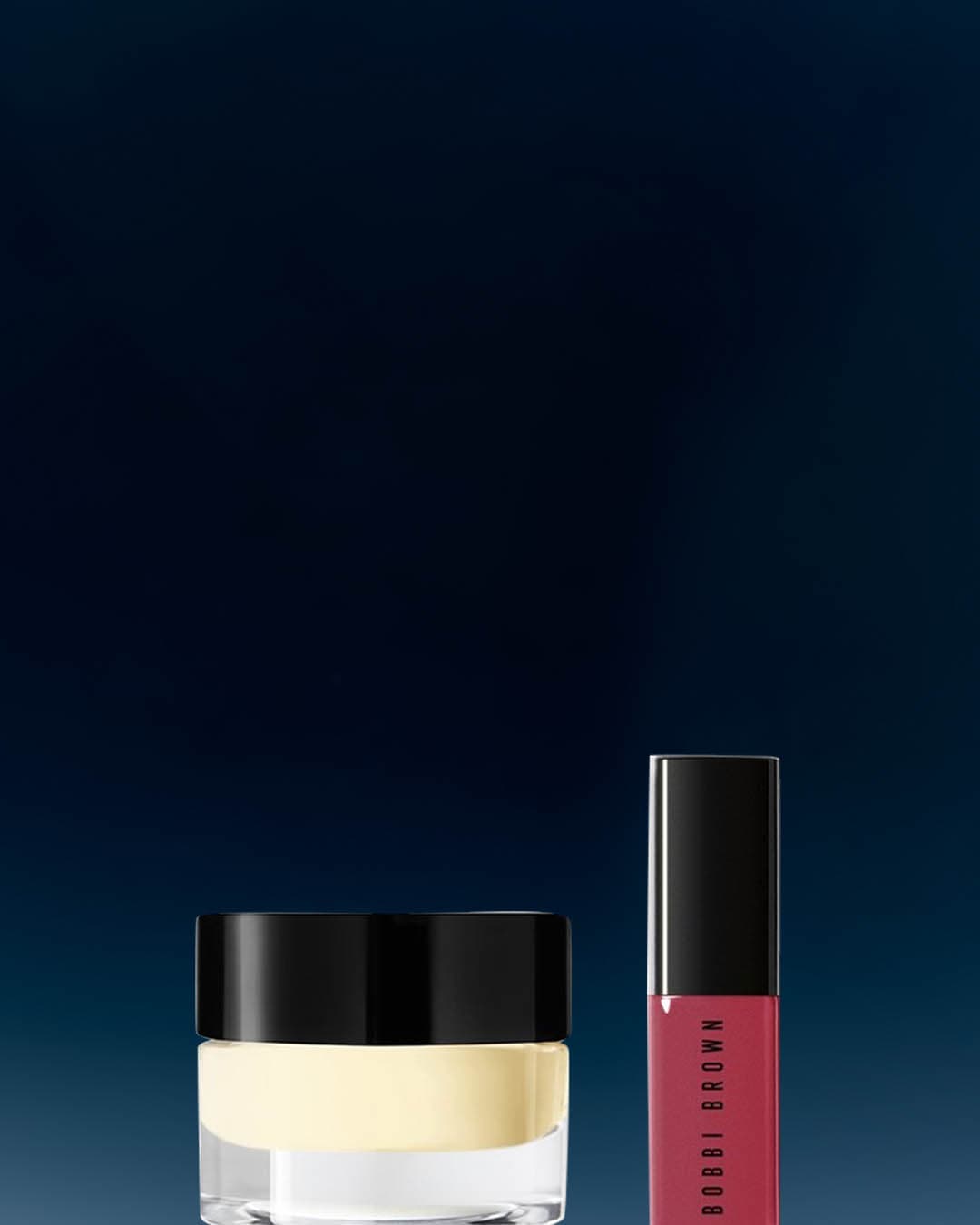 Na ciemnym tle znajdują się dwa produkty Bobbi Brown: krem w przezroczystym słoiczku z czarną nakrętką oraz błyszczyk do ust w smukłym opakowaniu z czarnym aplikatorem.