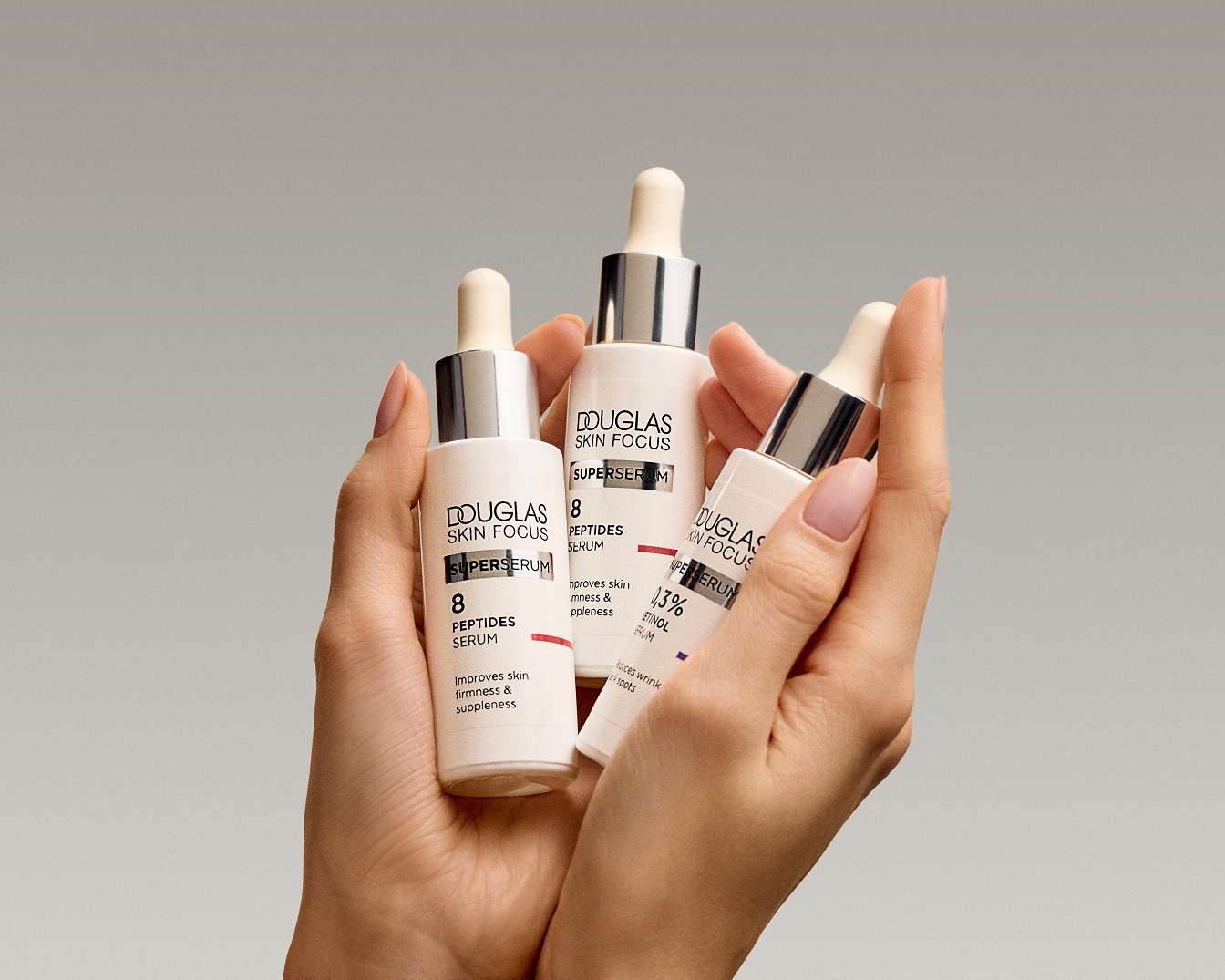 Pohľad zblízka na tri biele fľaštičky séra Douglas Skin Focus s pipetami, ktoré zlepšujú pevnosť a pružnosť pokožky.