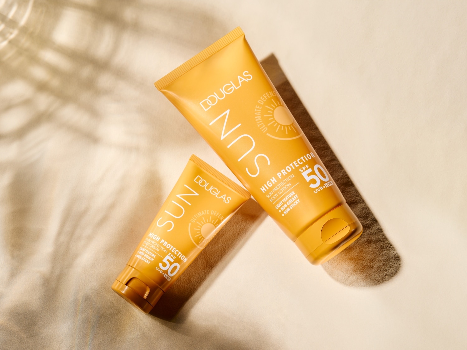 Voici deux tubes jaunes de crème solaire Douglas Sun SPF 50, offrant une haute protection avec une texture légère, non grasse et non collante.
