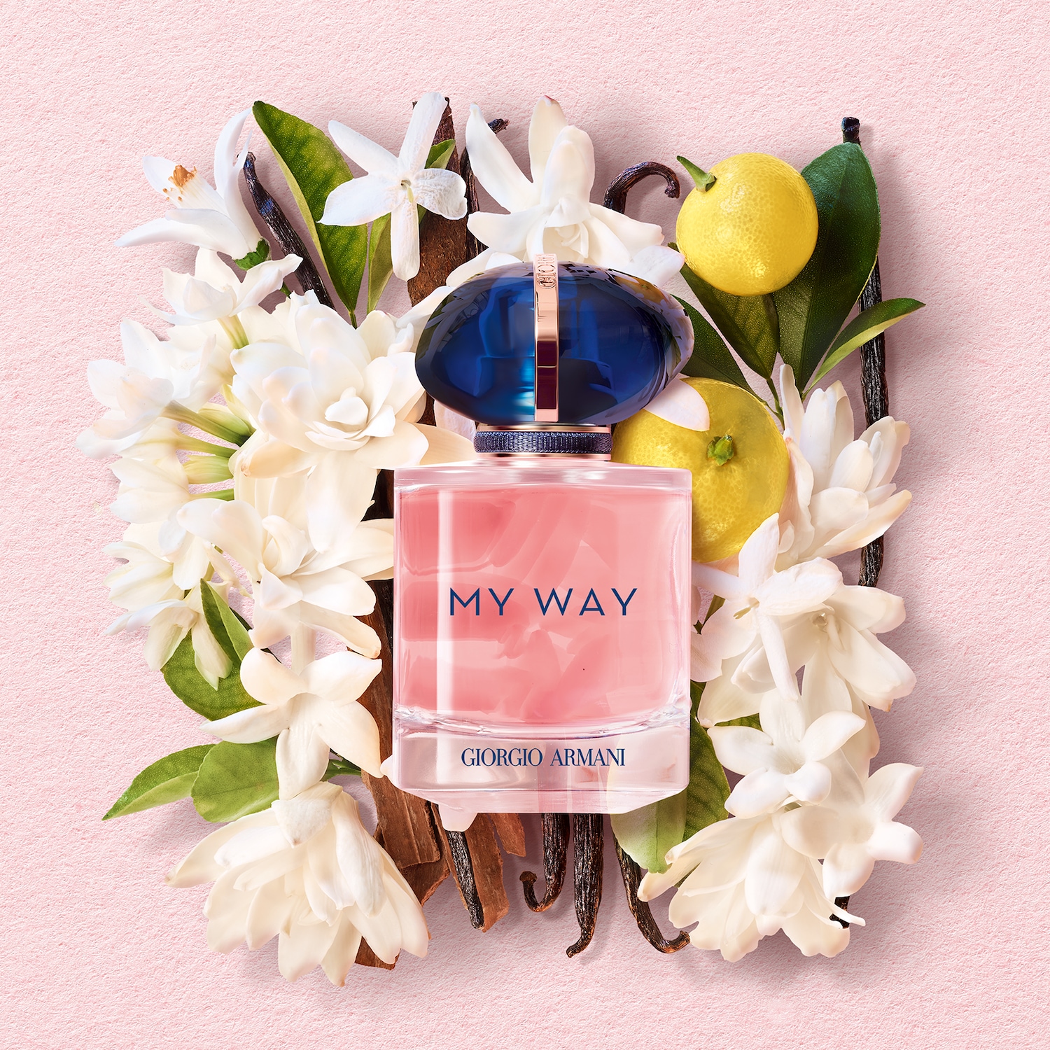 Lahvička parfému Giorgio Armani My Way obklopená bílými květy, vanilkou a citrony na růžovém pozadí.