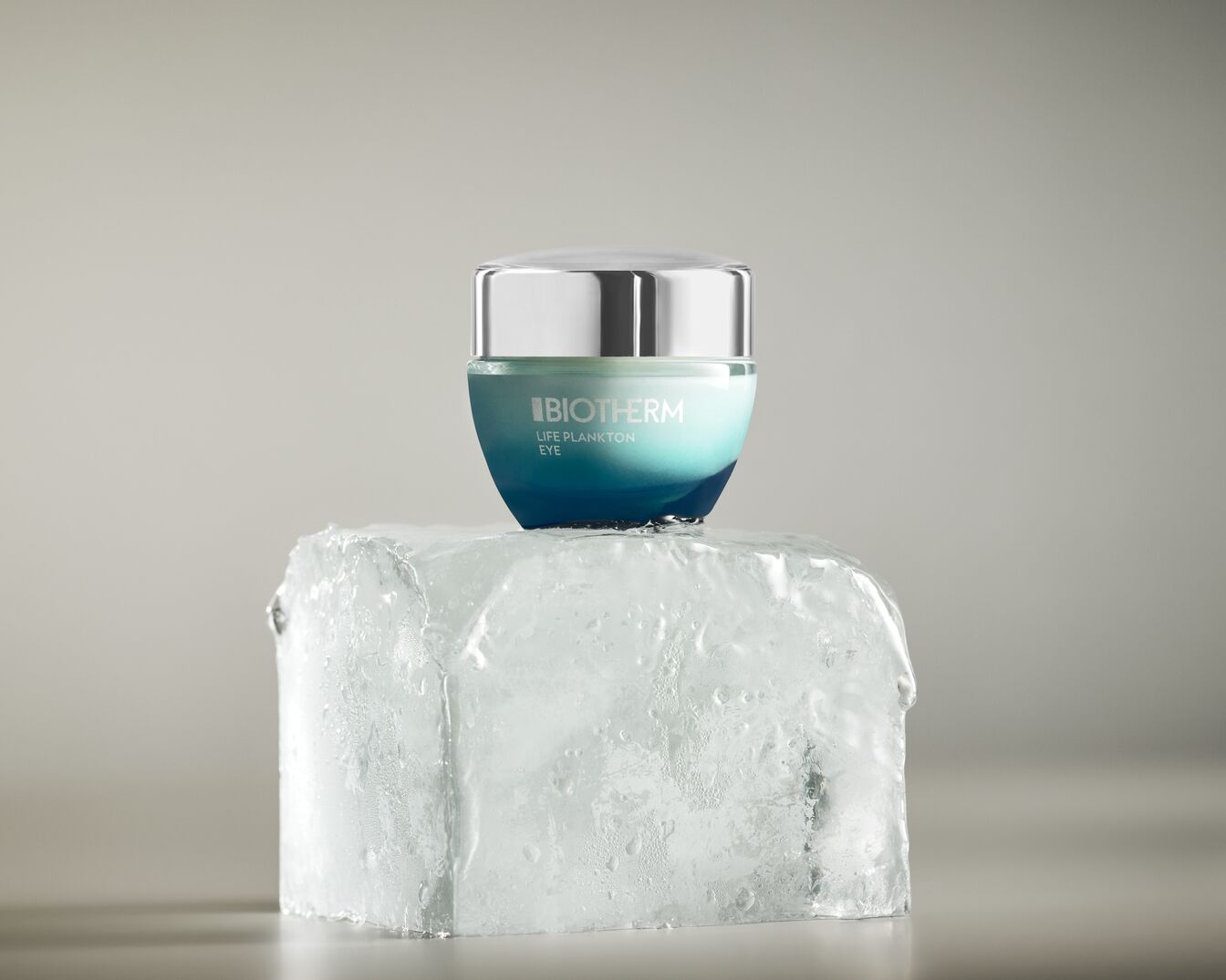 Die Biotherm Life Plankton Eye Creme in einem blau-weißen Tiegel mit silbernem Deckel steht auf einem Eisblock.