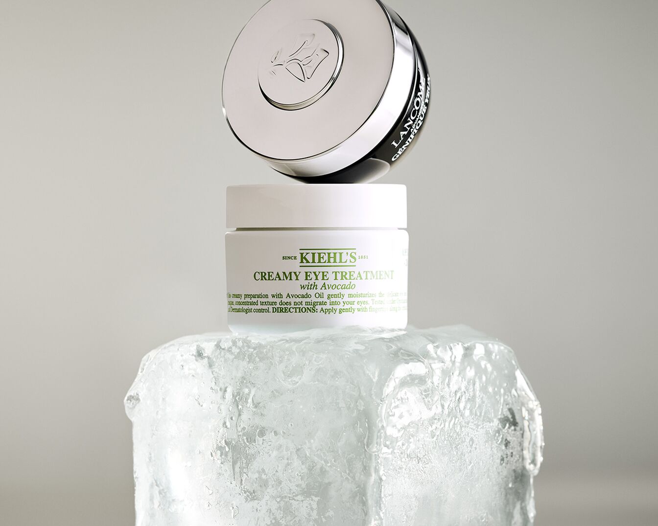 Kiehl's Creamy Eye Treatment mit Avocado auf einem Eisblock, darüber Lancôme Génifique Yeux mit silbernem Deckel.