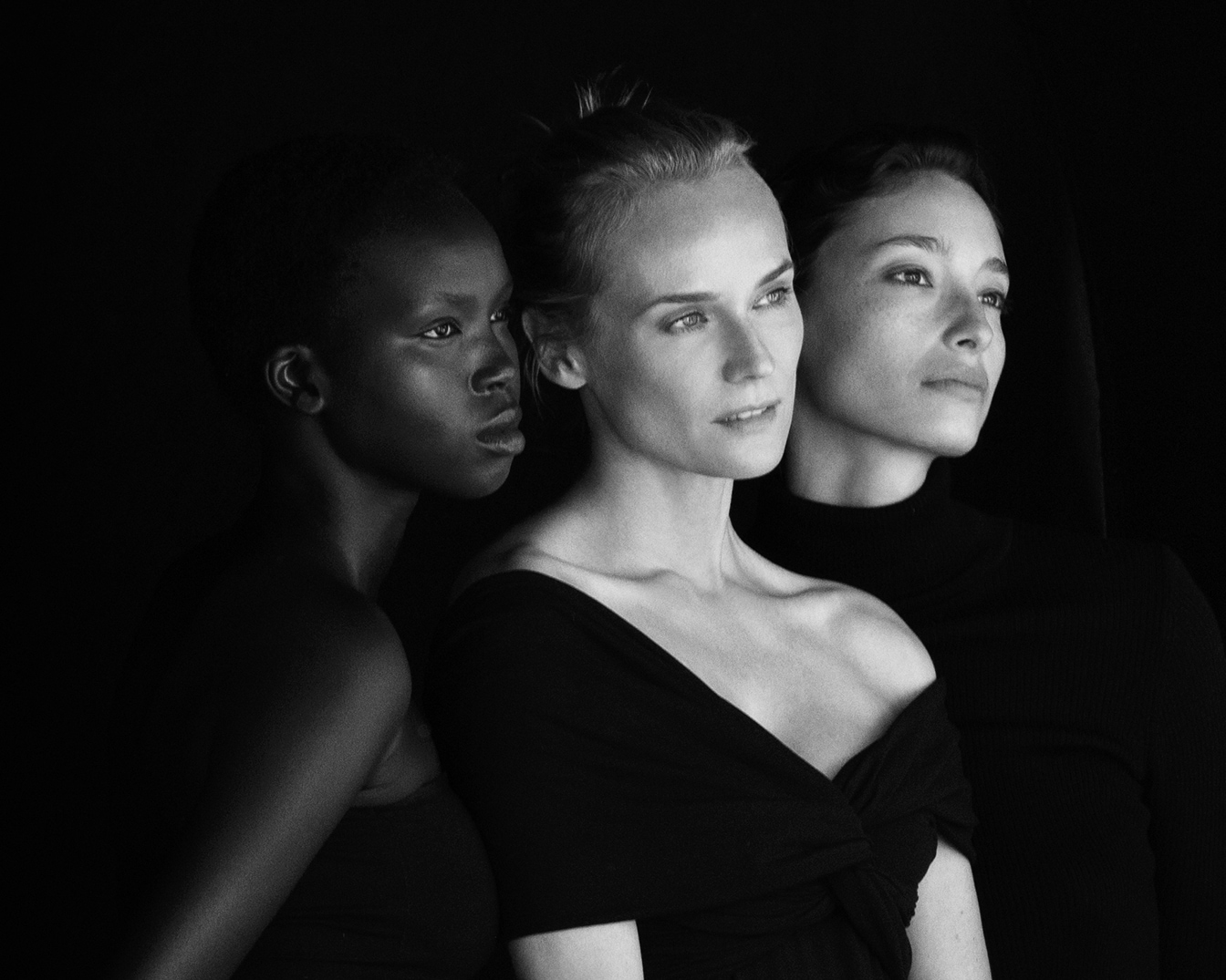 In un intenso ritratto in bianco e nero, tre donne di diversa etnia guardano nella stessa direzione, incarnando unità e forza.