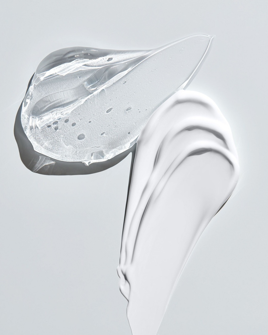 Nahaufnahme von transparentem Gel und weißer Creme, die die Texturen und Formulierungen von Hautpflegeprodukten hervorhebt.