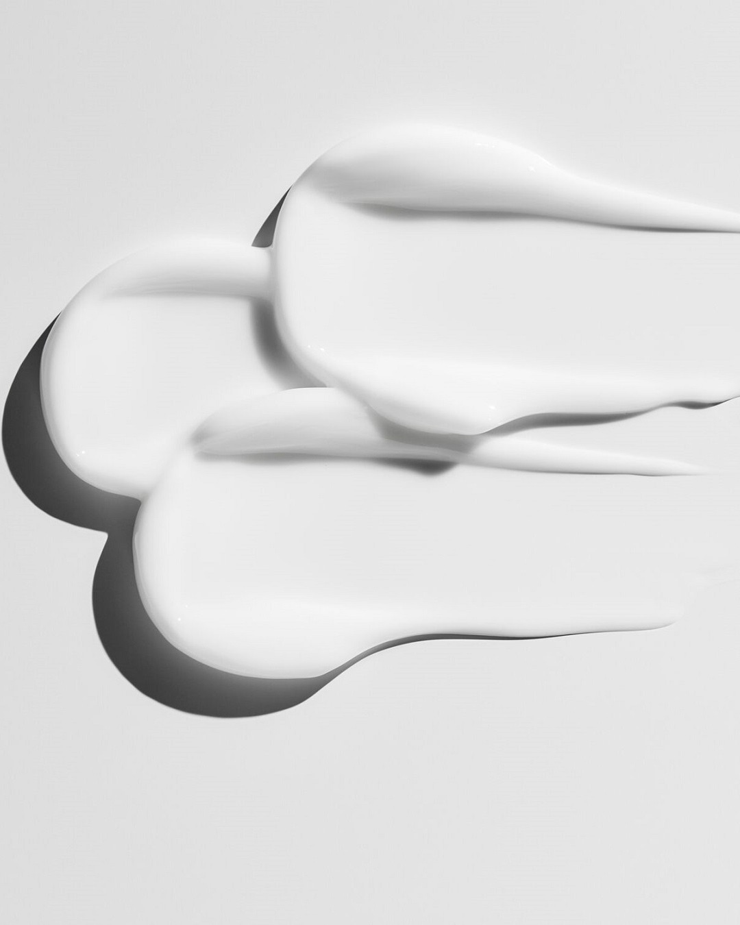 Nahaufnahme von weißen, cremigen Hautpflegeprodukten, die eine glatte und reichhaltige Textur zeigen.