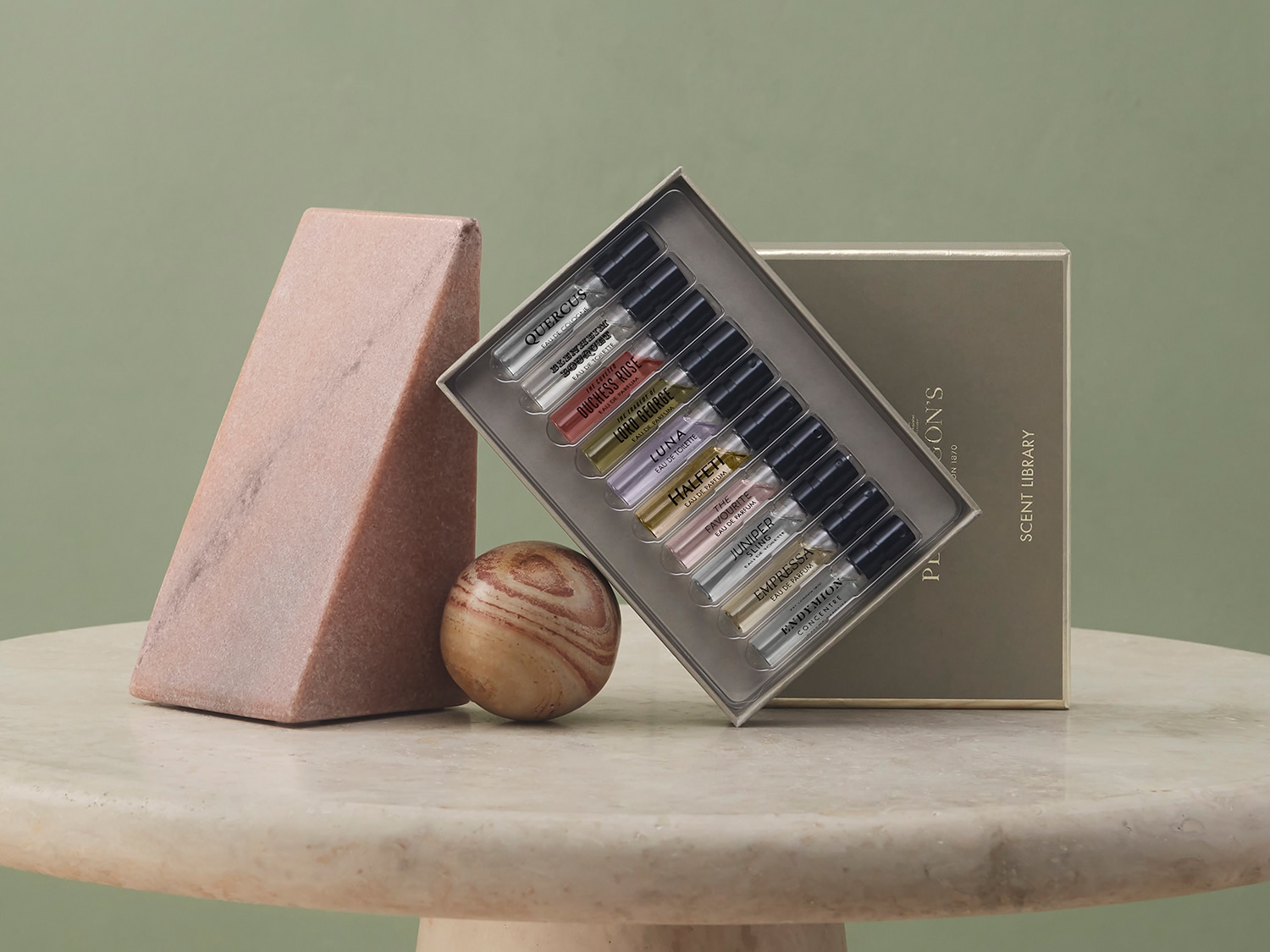 Eine Auswahl an Penhaligon's Düften in kleinen Glasfläschchen, präsentiert in einer eleganten Geschenkbox, umgeben von dekorativen Marmorobjekten.