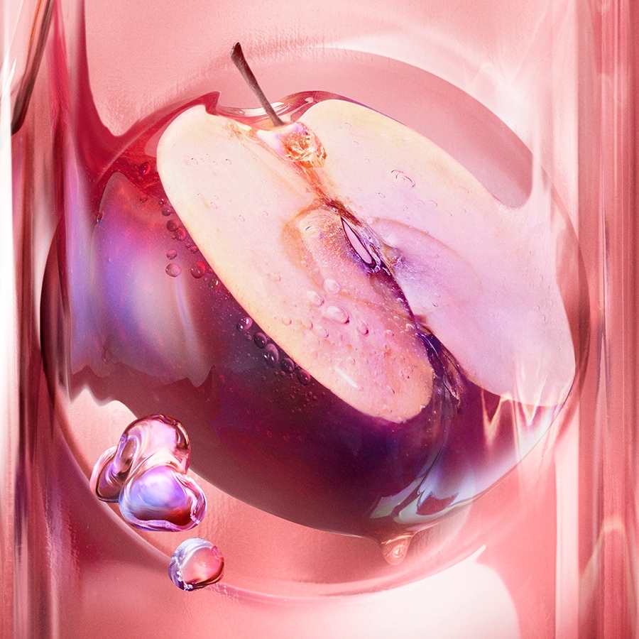 Nahaufnahme einer halbierten Pflaume in einer transparenten Flüssigkeit, die die Frische und Reinheit des Produkts hervorhebt.