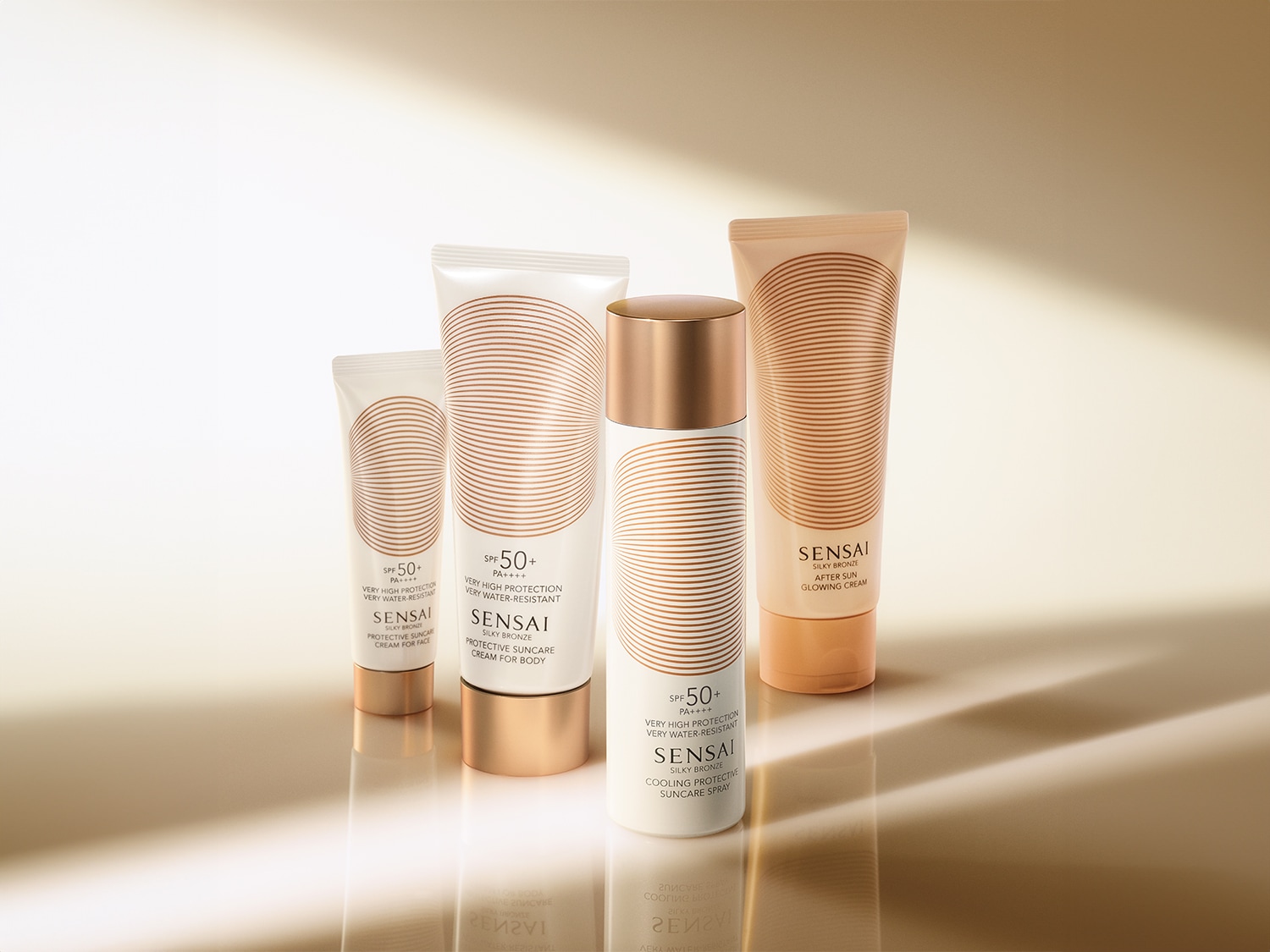 Vier Sensai Silky Bronze zonbeschermingsproducten, waaronder crème voor gezicht en lichaam, een spray en een aftersun, allemaal met SPF 50 en een witte verpakking met gouden details.