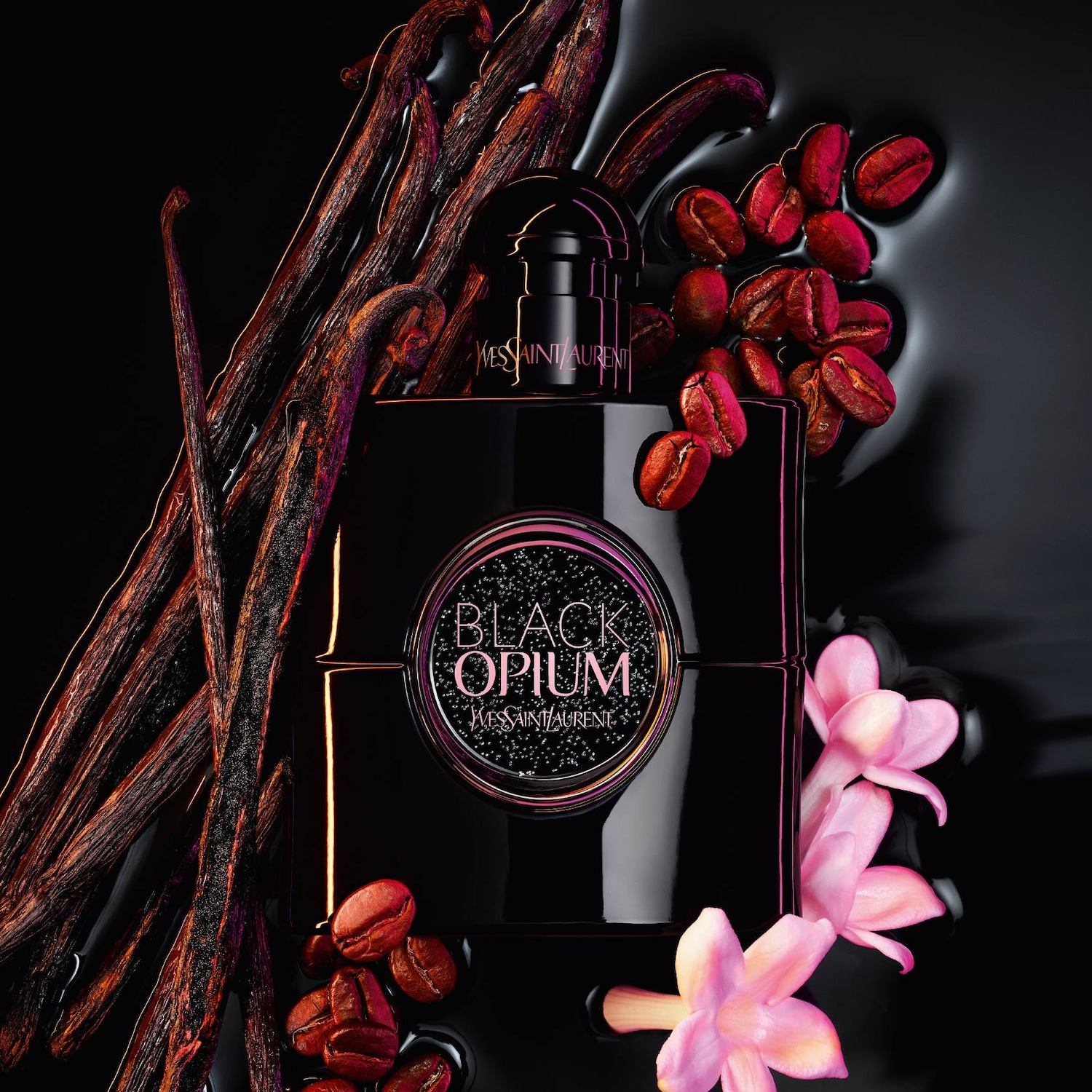 A Black Opium parfümös üveg látható vaníliarudakkal, kávészemekkel és rózsaszín virágokkal körülvéve, melyek a parfüm összetevőit szimbolizálják.