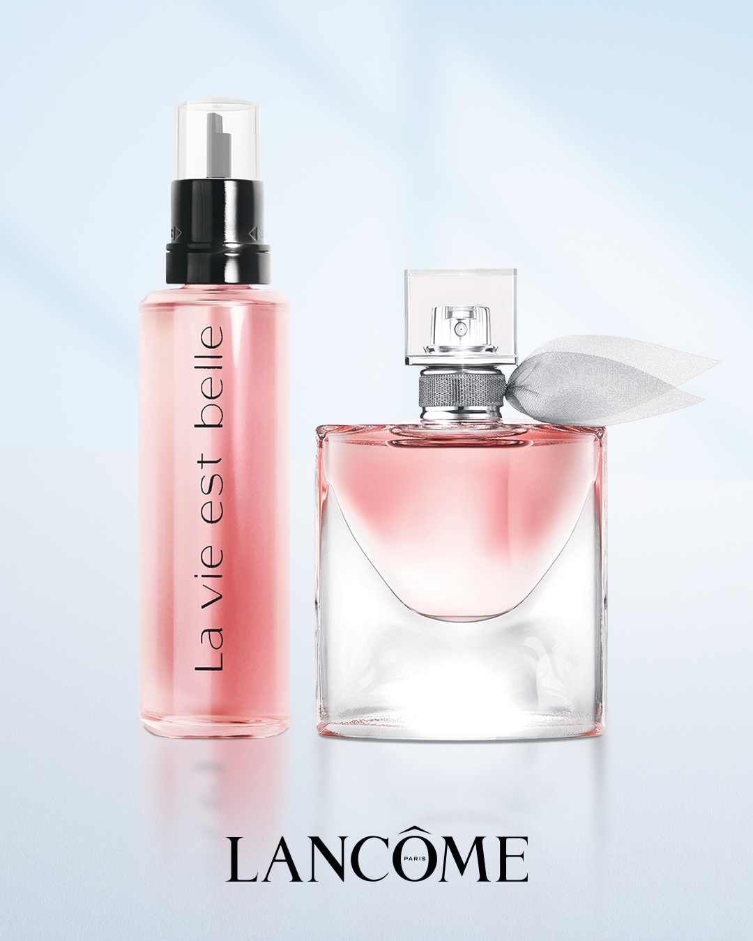 Zwei Lancôme-Parfümflaschen, eine mit der Aufschrift La vie est belle, stehen vor einem hellen Hintergrund.