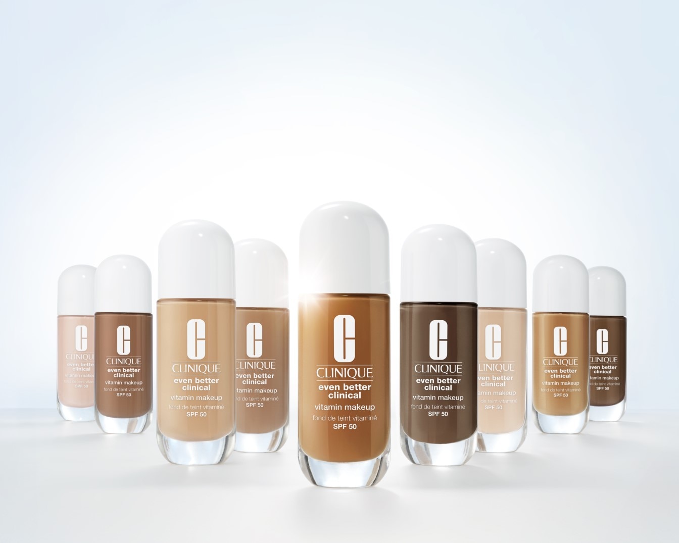 Różne odcienie podkładu Clinique Even Better Clinical Vitamin Makeup SPF 50 w szklanych butelkach z białymi zakrętkami, zapewniające nieskazitelne wykończenie.