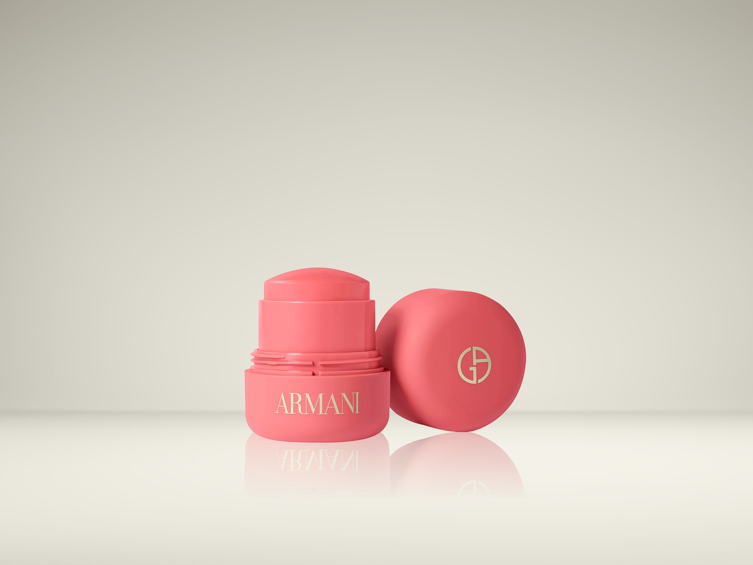 Een open koraalroze Armani-blushstick met gouden letters en een bijpassende dop met het GA-logo, die een stralende gloed belooft.