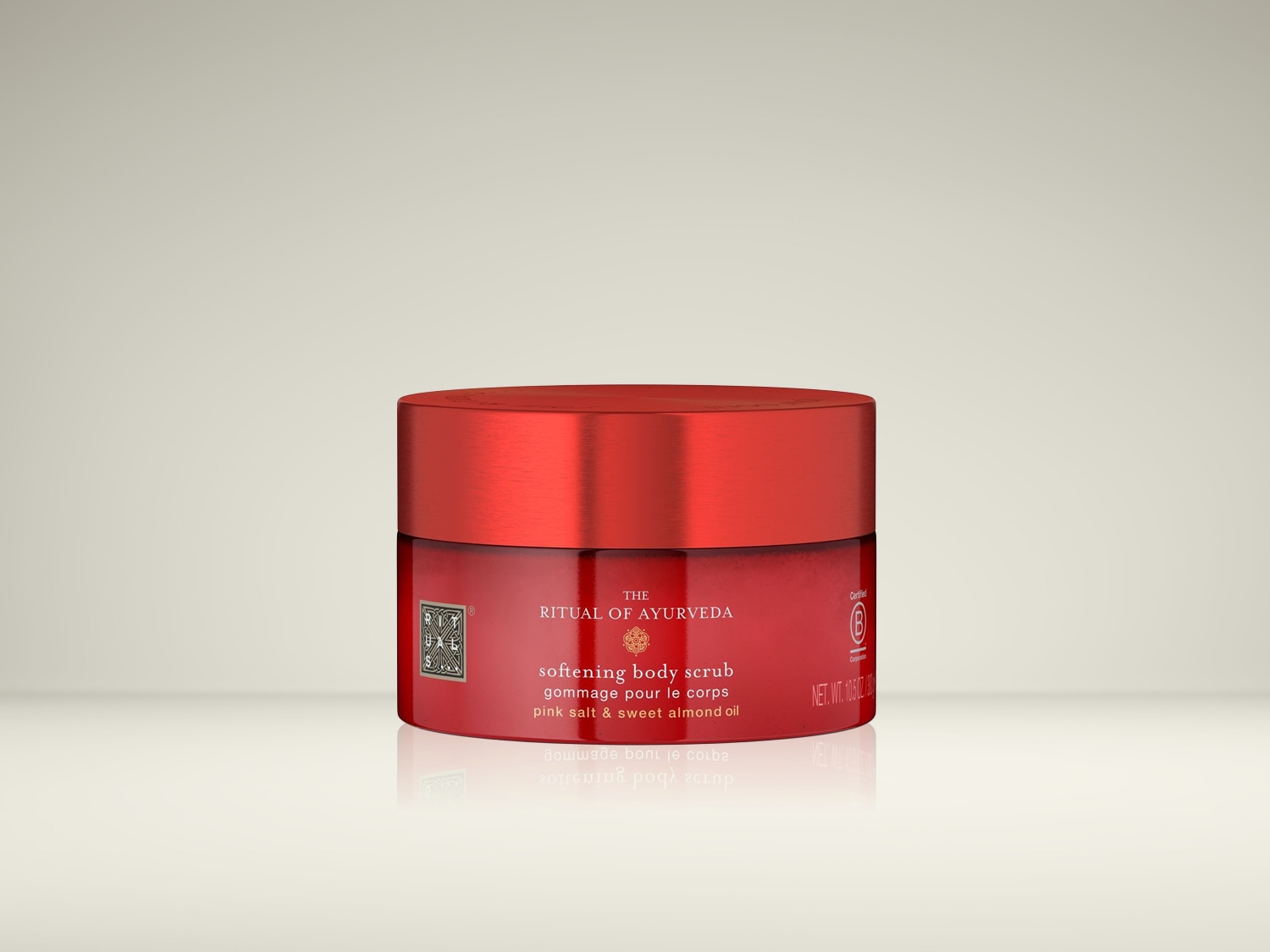 Le gommage corporel adoucissant The Ritual of Ayurveda, présenté dans un pot rouge avec un couvercle assorti, contient du sel rose et de l'huile d'amande douce pour une peau soyeuse.