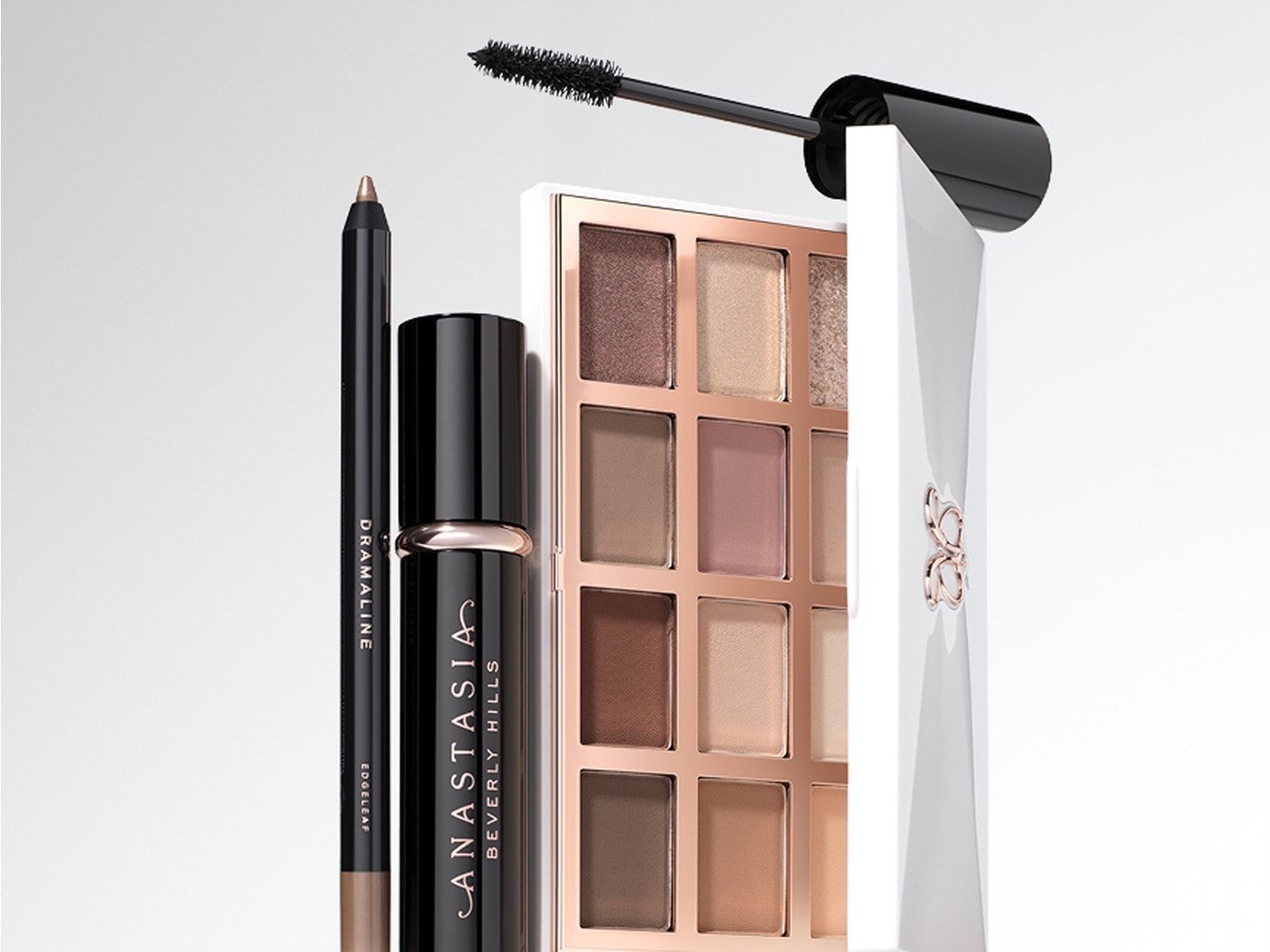 Een Anastasia Beverly Hills oogschaduwpalet met 12 tinten in bruin- en roségoudtinten, een zwarte mascara en een bruin oogpotlood, perfect voor een complete ooglook.
