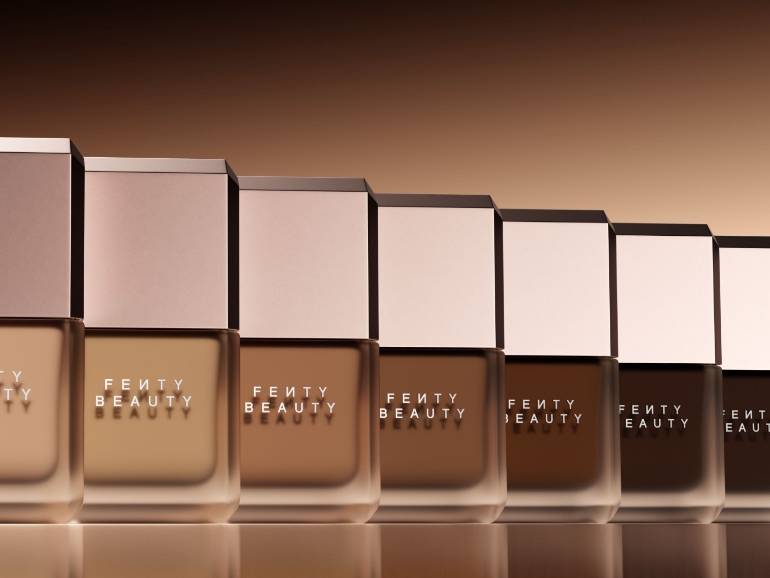 Découvrez la gamme complète de fonds de teint Fenty Beauty, présentée dans des flacons en verre dépoli avec des bouchons carrés de couleur chair, offrant une variété de teintes pour toutes les carnations.