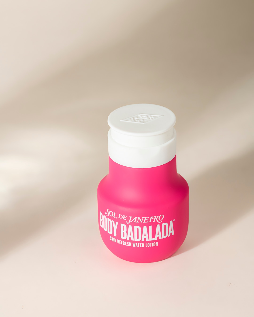 Découvrez la lotion rafraîchissante pour le corps Sol de Janeiro Body Badalada, présentée dans une bouteille rose vif avec un bouchon blanc, parfaite pour une peau hydratée et éclatante.
