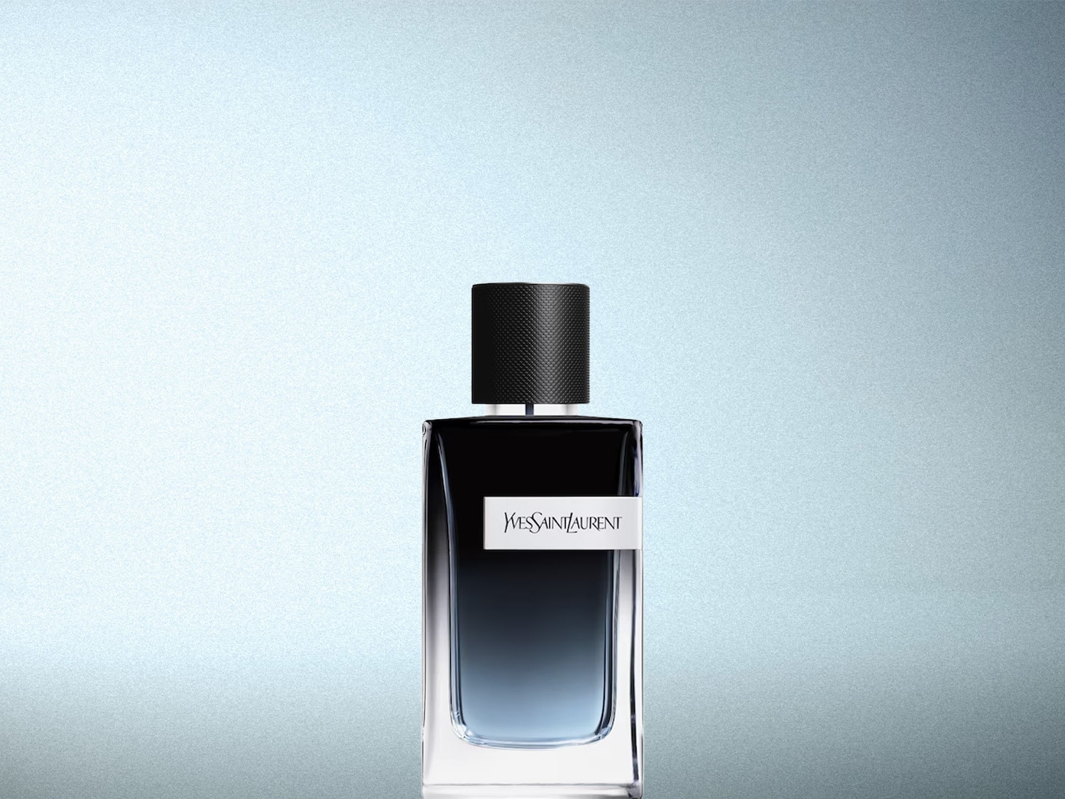 Le parfum Yves Saint Laurent Y pour homme est présenté dans un flacon rectangulaire en verre transparent, avec un dégradé de couleur allant du noir intense en haut au bleu clair en bas, et un bouchon noir texturé.