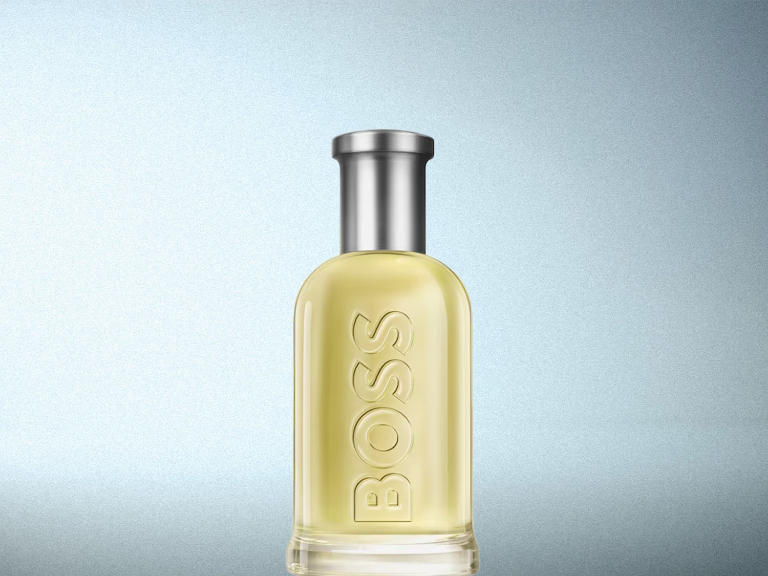 Le parfum BOSS Bottled Eau de Toilette est présenté dans un flacon en verre transparent avec un liquide jaune pâle et un bouchon argenté, le nom "BOSS" est gravé verticalement sur le flacon.