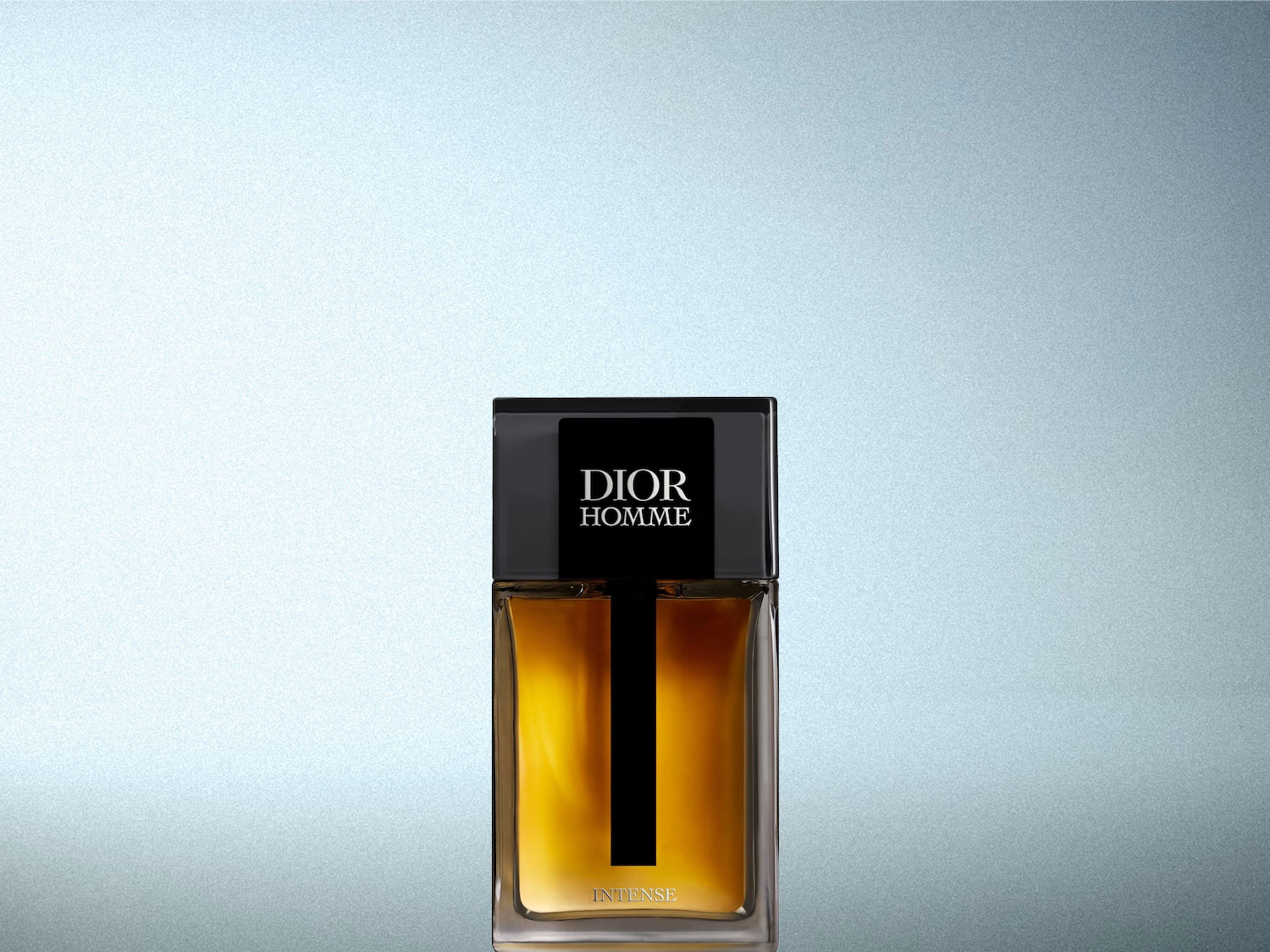 Le parfum Dior Homme Intense est présenté dans une bouteille en verre rectangulaire avec un liquide ambré et un capuchon noir, le nom "DIOR HOMME" est écrit en blanc sur le capuchon.