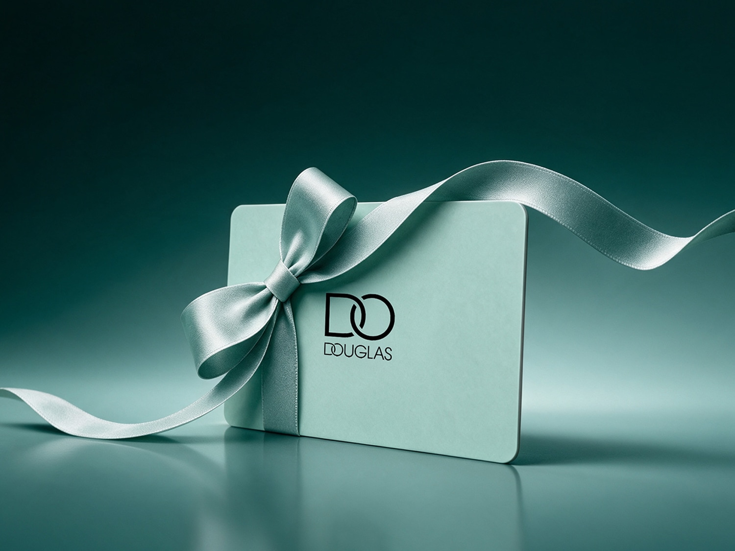 Une carte cadeau Douglas vert menthe est ornée d'un ruban de satin gris-vert noué en un élégant nœud, avec le logo Douglas en noir au centre.