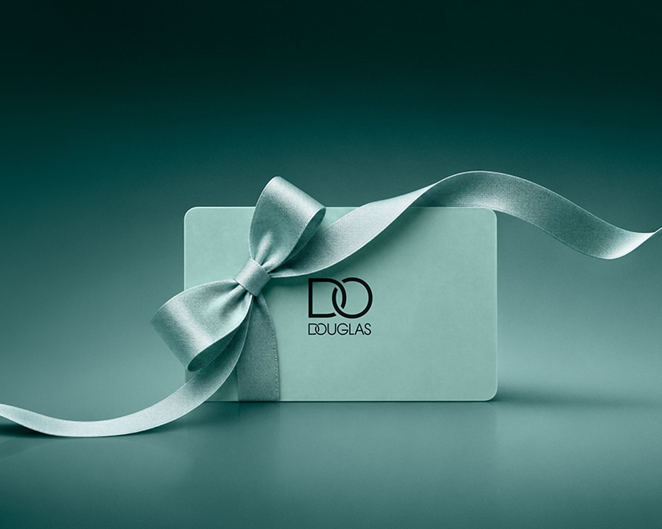 Une carte cadeau Douglas bleu clair est ornée d'un ruban de soie bleu clair noué en un nœud élégant, avec le logo Douglas en noir au centre.