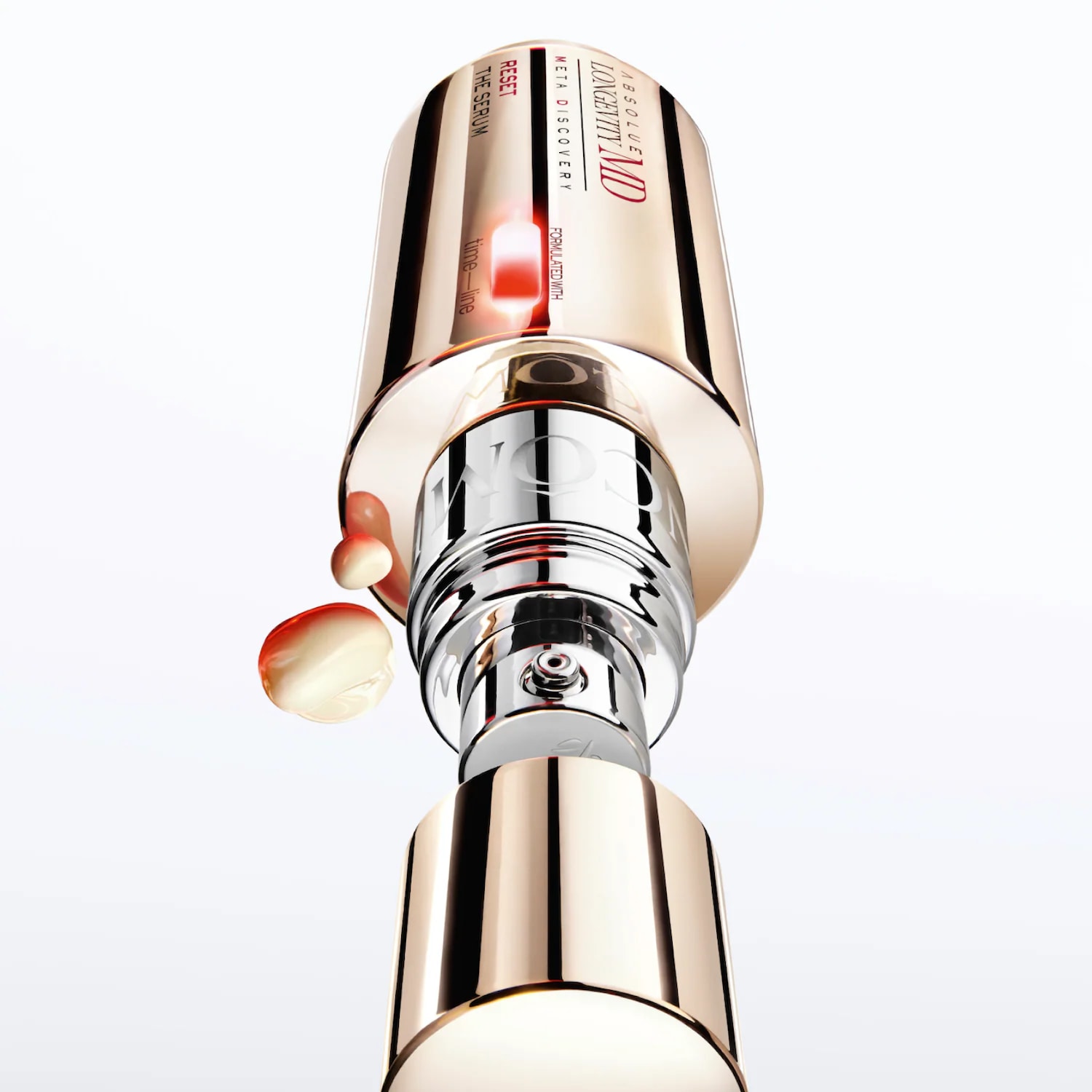 Le sérum Absolue Longevity MD Reset, dans un flacon doré et argenté, libère des gouttes de sérum blanc et orange, offrant une expérience de soin luxueuse.