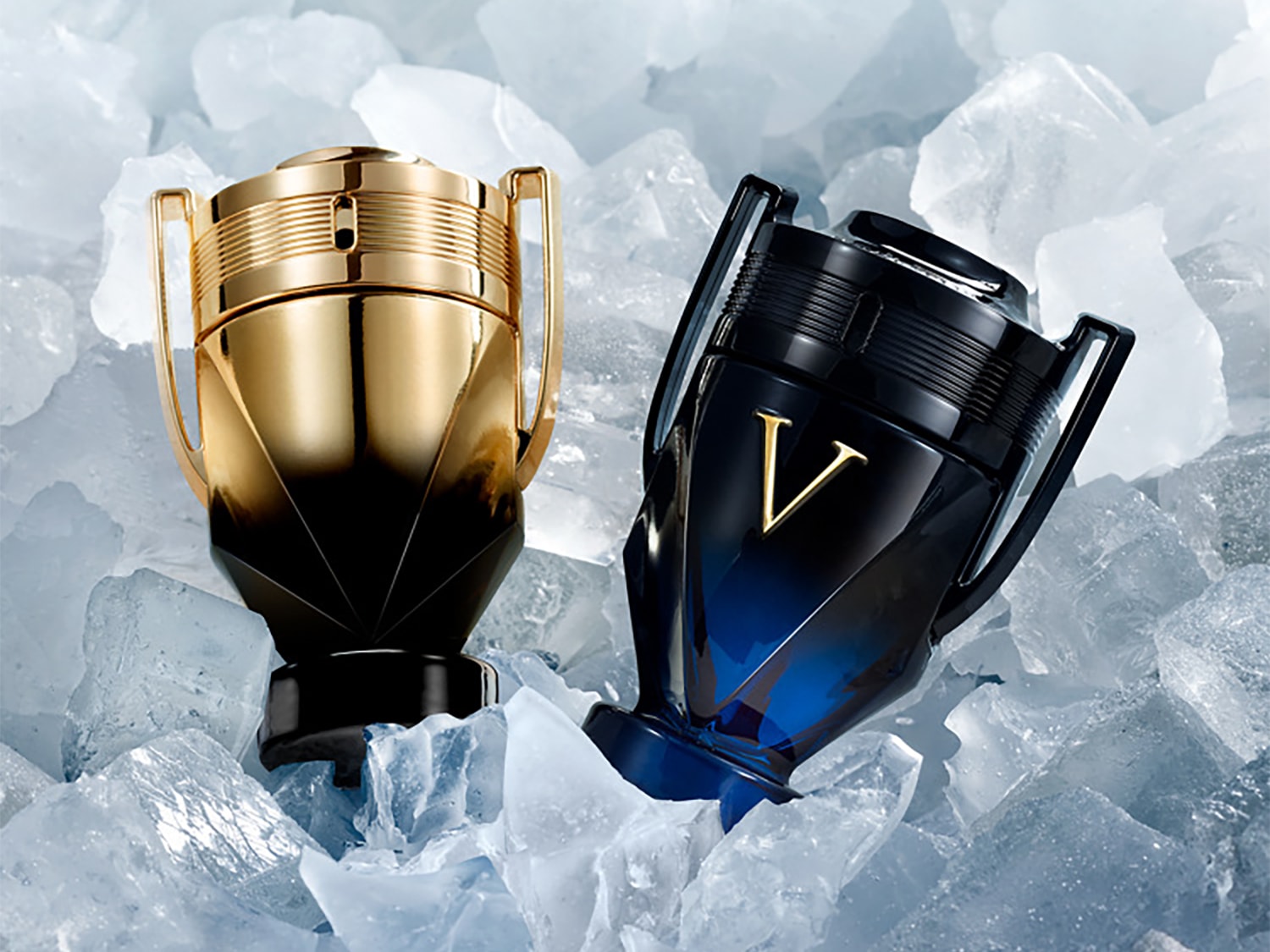 Due flaconi di profumo a forma di trofeo, uno dorato e nero e l'altro blu scuro e nero con una "V" dorata, sono adagiati su un letto di cubetti di ghiaccio.
