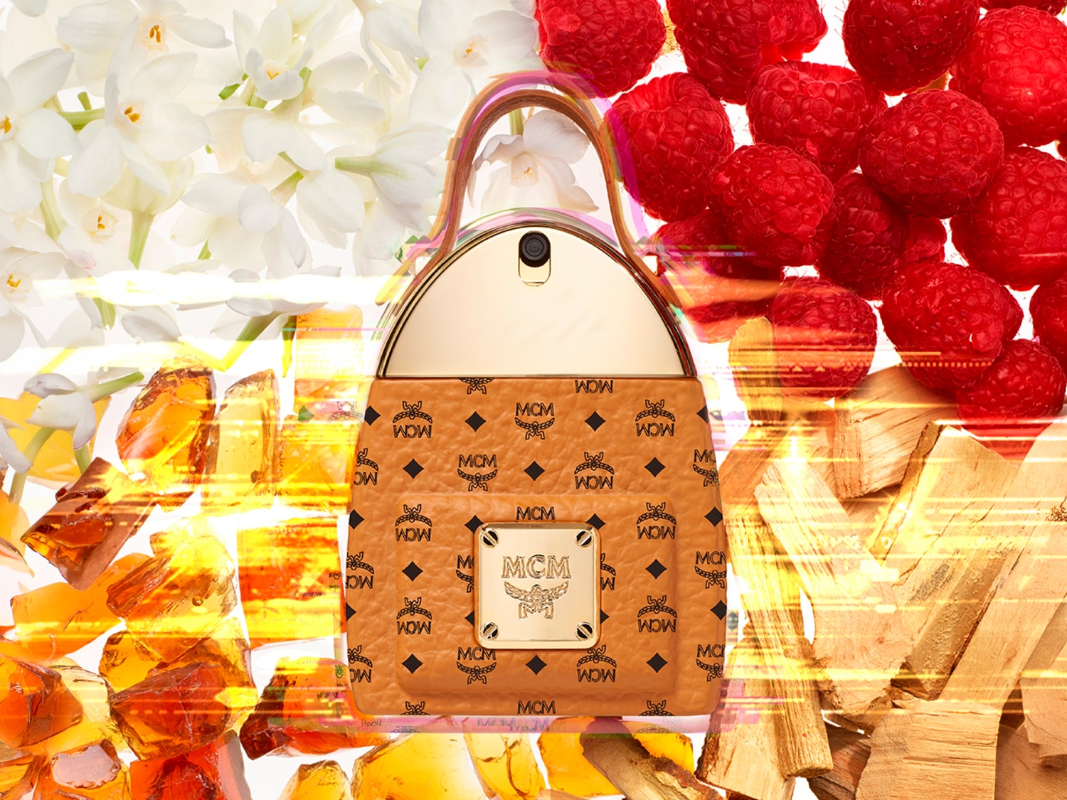 Der MCM Eau de Parfum Flakon in Form einer braunen Handtasche mit goldenen Akzenten ist umgeben von weißen Blüten, roten Himbeeren, goldenem Bernstein und Holzstücken, die die Duftnoten symbolisieren.