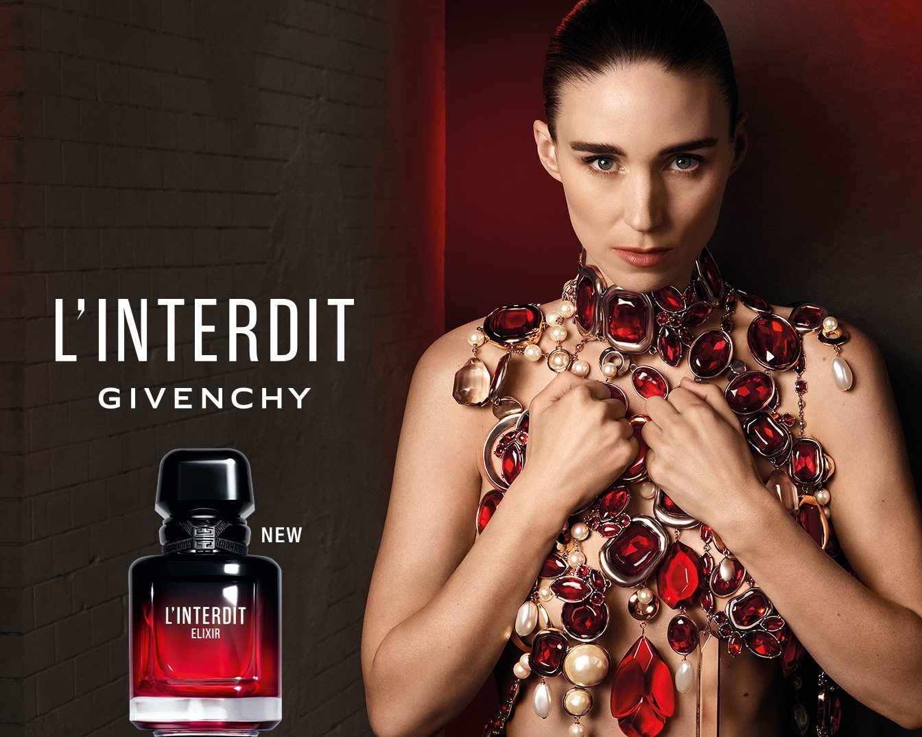 L'Interdit Givenchy, un parfum nou, este prezentat într-o sticlă elegantă, cu un design negru și roșu, alături de o femeie cu părul prins, purtând un colier statement din pietre roșii și perle.