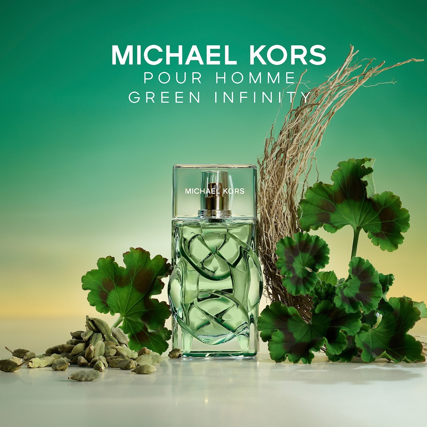 Le parfum Michael Kors Pour Homme Green Infinity est présenté dans un flacon en verre vert clair avec un bouchon transparent, entouré de feuilles vertes et de gousses de cardamome, sur un fond dégradé de vert et de jaune.