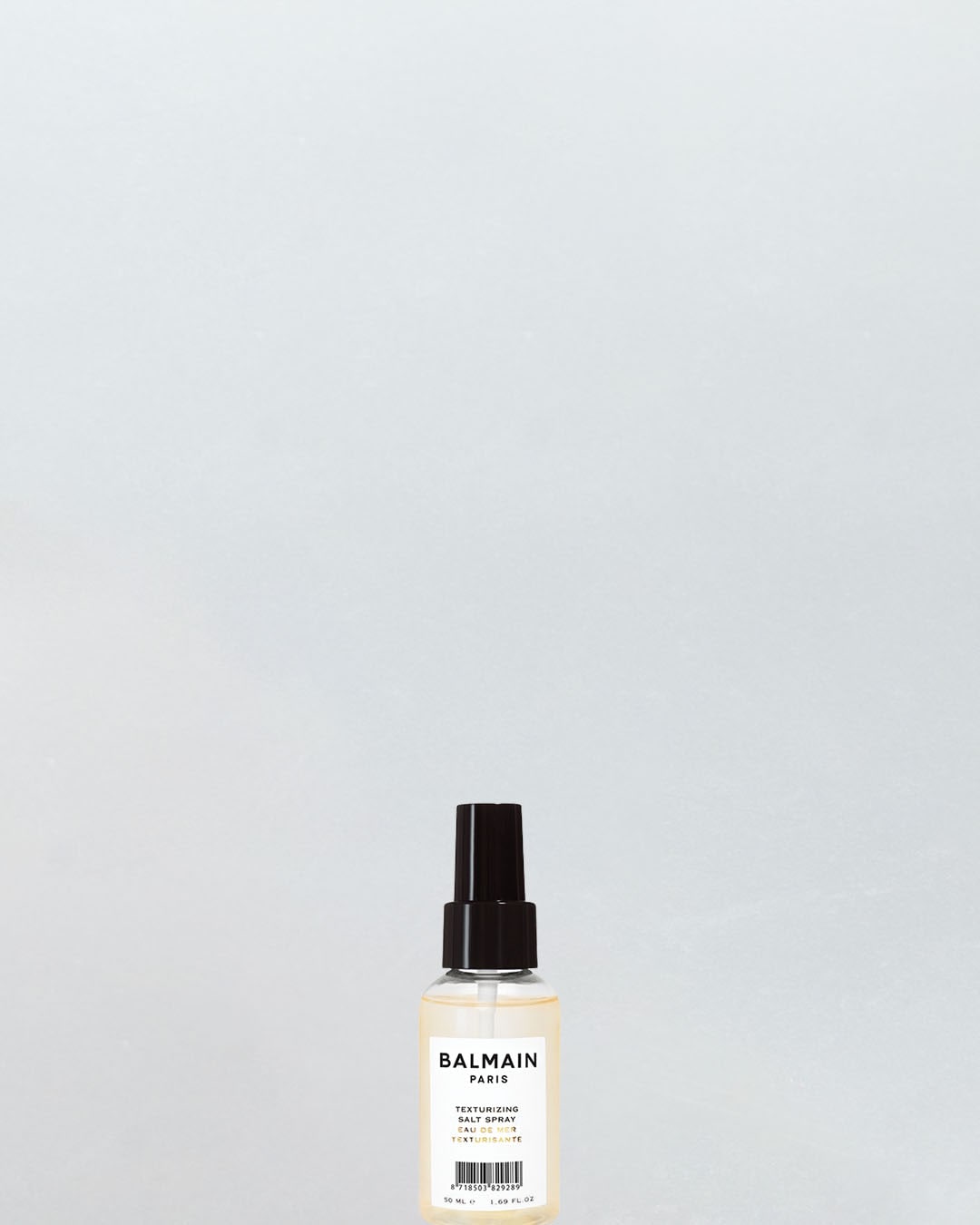 Balmain Paris Texturizing Salt Spray to 50 ml butelka z czarną pompką, zawierająca jasnożółty płyn, idealna do stylizacji włosów.