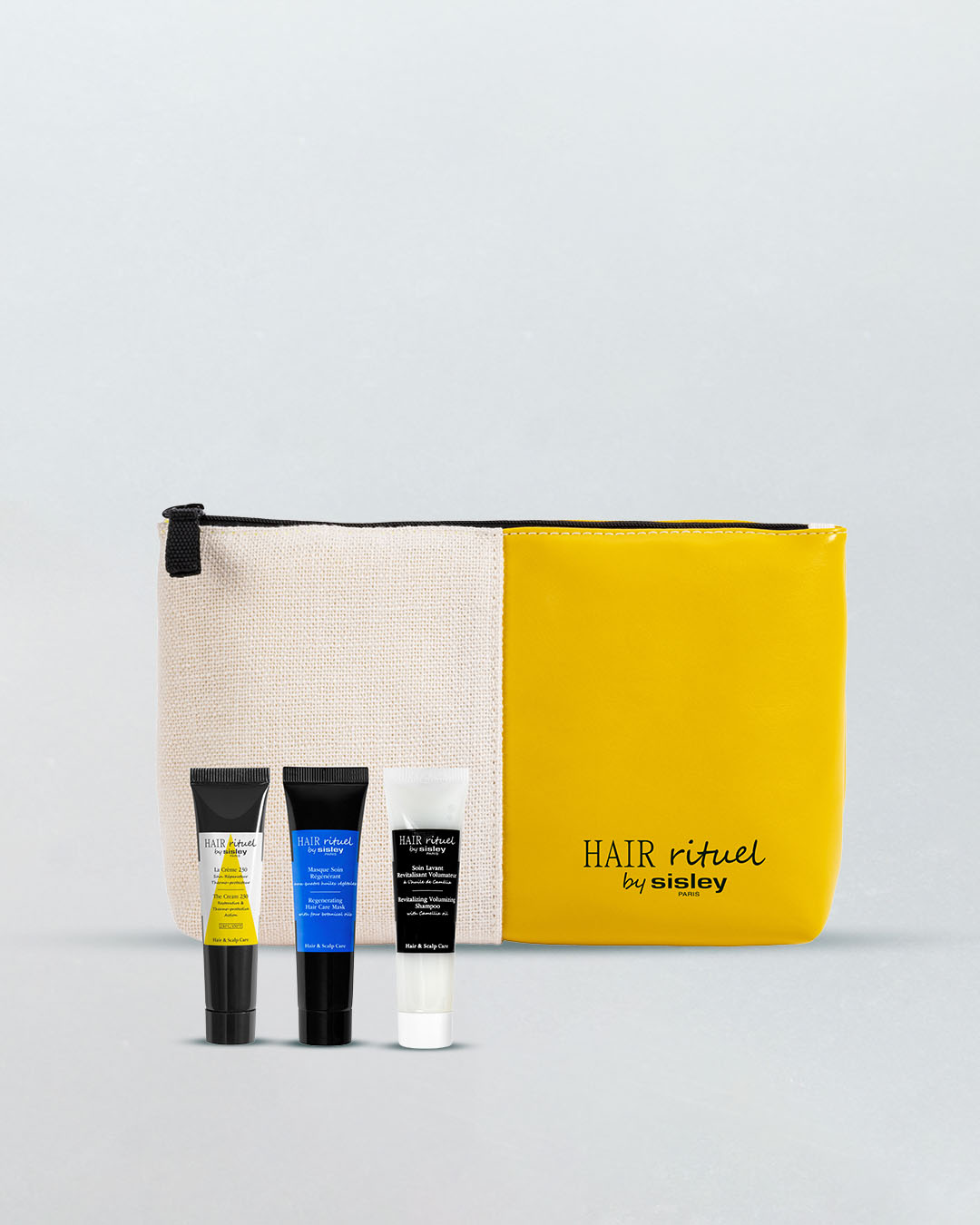 Zestaw Hair Rituel by Sisley zawiera trzy miniaturowe produkty do pielęgnacji włosów: krem, maskę i szampon, zapakowane w elegancką kosmetyczkę w kolorze beżowo-żółtym.
