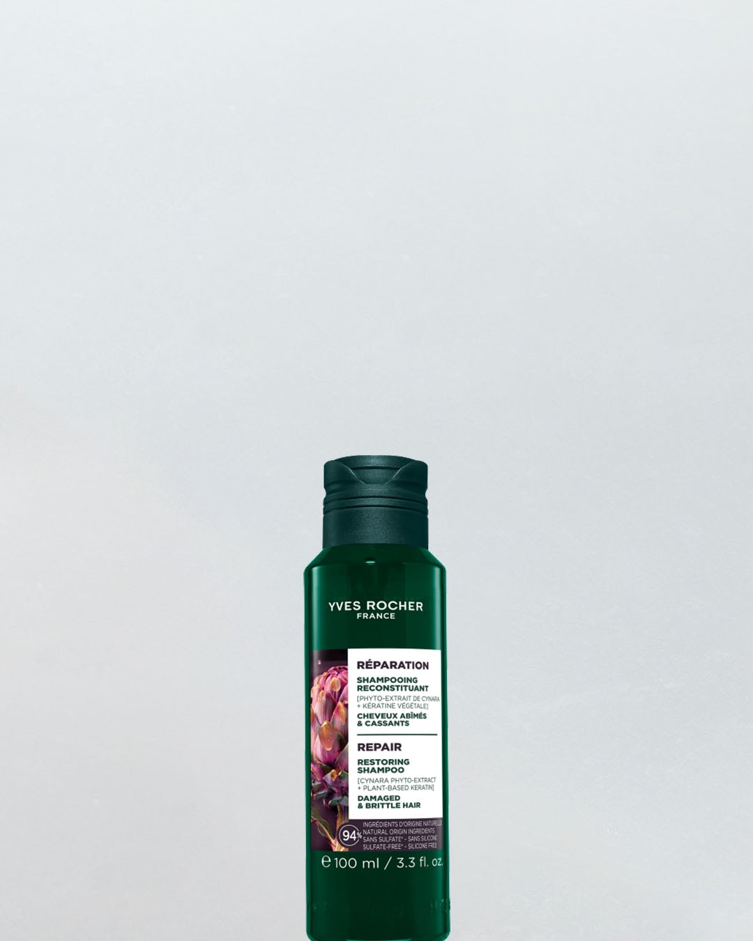 Yves Rocher Repair Restoring Shampoo w zielonej butelce z ciemnozieloną zakrętką, z grafiką karczocha i informacją o 94% składników pochodzenia naturalnego, idealny do włosów zniszczonych i łamliwych.