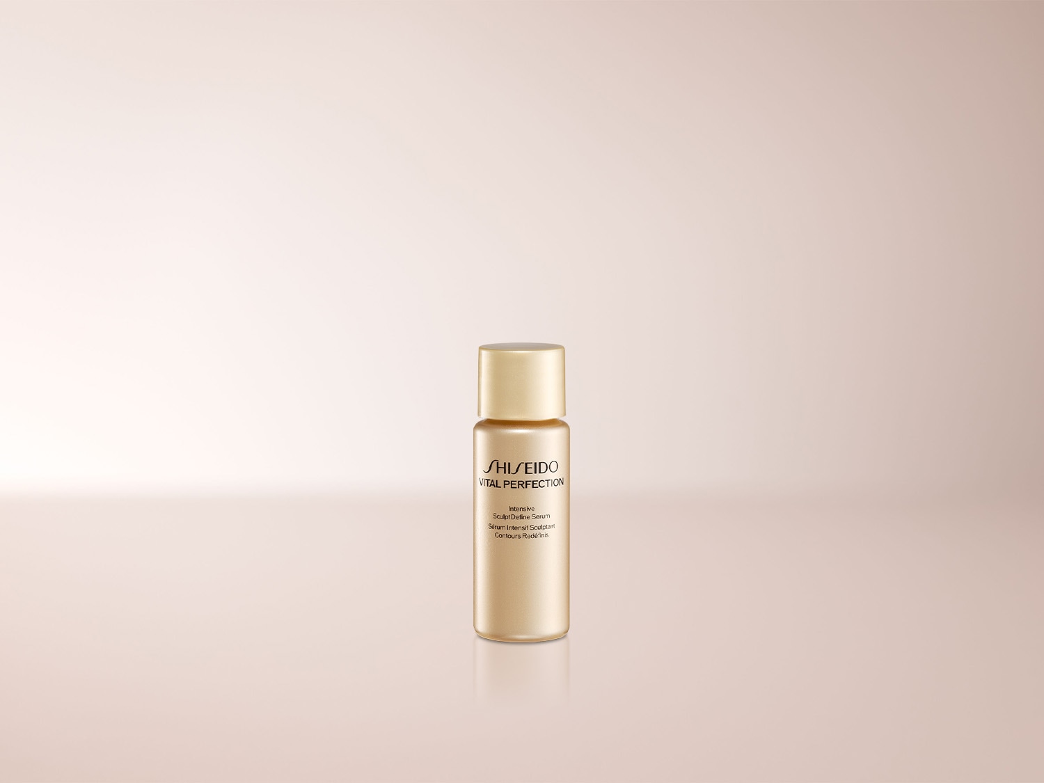 Die Shiseido Vital Perfection Intensive Sculpting Serum Flasche ist goldfarben mit einem passenden goldenen Deckel und steht auf einem hellrosa Hintergrund.