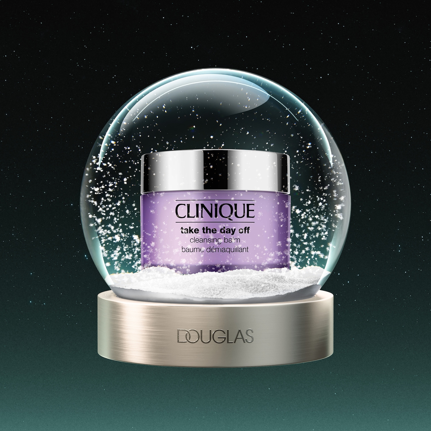 Een Clinique Take The Day Off Cleansing Balm in een paarse pot met zilveren deksel, geplaatst in een sneeuwbol met witte sneeuwvlokken en de naam Douglas op de gouden voet, tegen een donkergroene sterrenhemel.