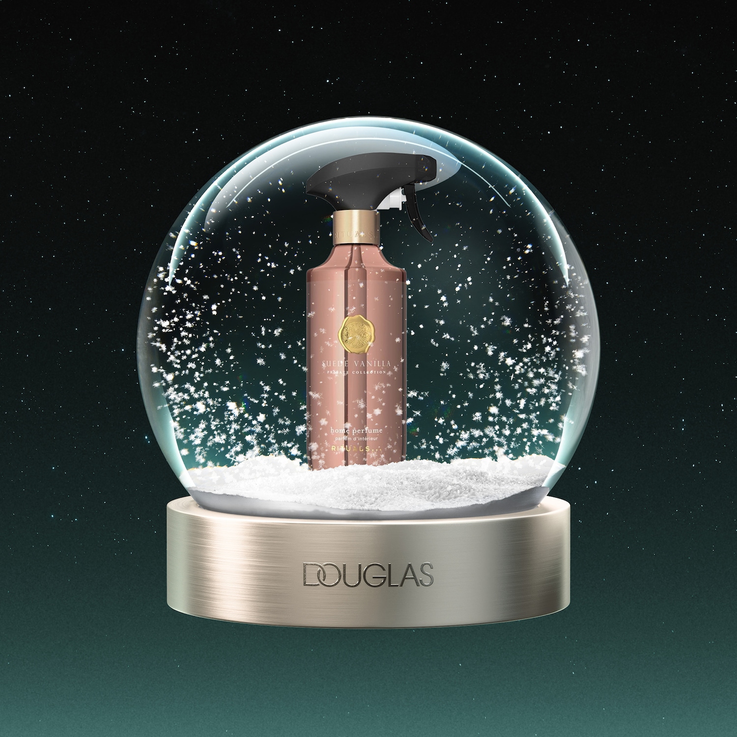 Een Rituals Suede Vanilla Private Collection huisparfum in een roségouden fles met zwarte spuitkop, staat in een sneeuwbol met witte sneeuwvlokken en een gouden basis met het Douglas-logo, tegen een donkergroene sterrenhemel.