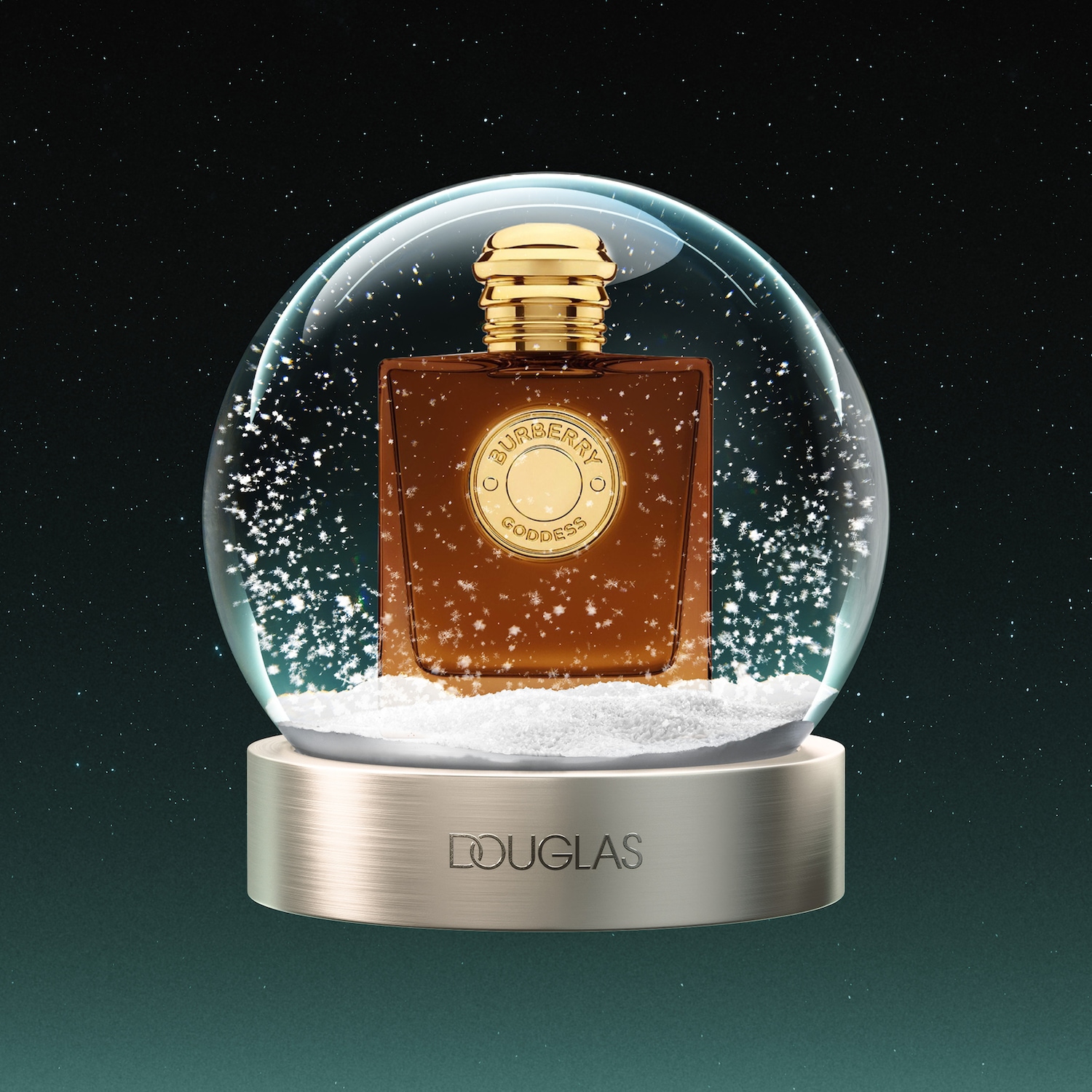 Een Burberry Goddess parfumflesje in een sneeuwbol, met een gouden dop en een rond gouden etiket met de tekst "BURBERRY GODDESS", omringd door vallende sneeuwvlokken en een donkere, sterrenhemelachtergrond.