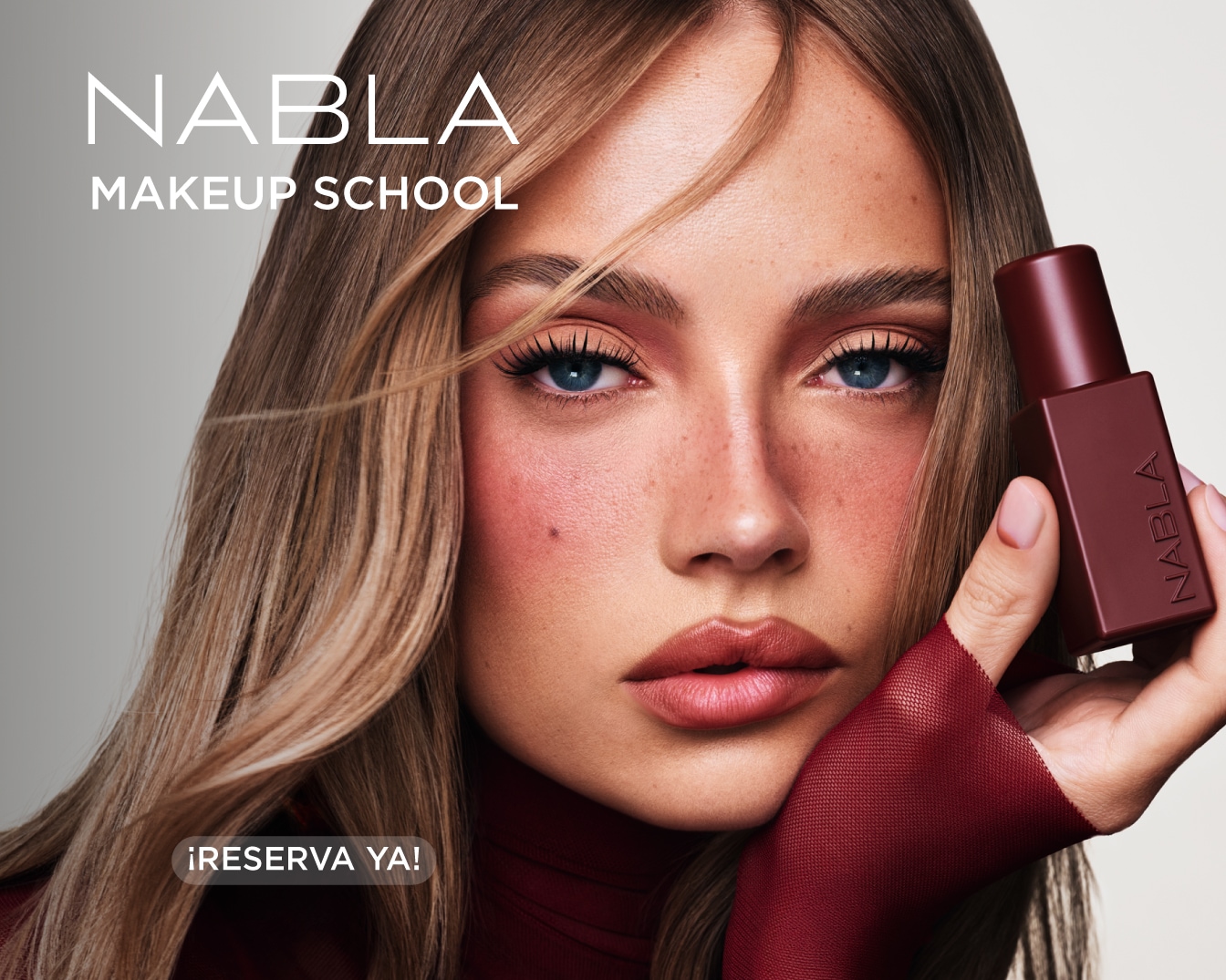 Una mujer con cabello castaño claro y ojos azules, con maquillaje de ojos rosa y mejillas sonrojadas, sostiene un frasco de maquillaje marrón oscuro de NABLA, con el texto "NABLA MAKEUP SCHOOL" y "¡RESERVA YA!".