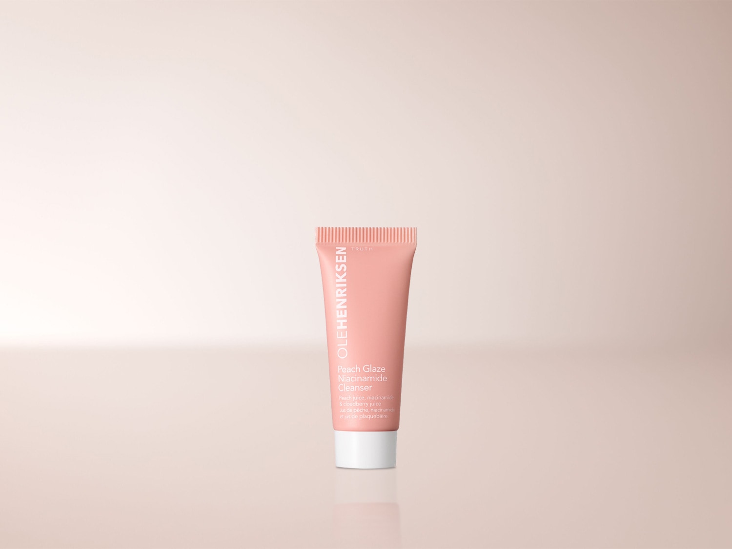Der OLEHENRIKSEN Peach Glaze Niacinamide Cleanser in einer pfirsichfarbenen Tube mit weißer Kappe reinigt die Haut sanft mit Pfirsichsaft, Niacinamid und Moltebeersaft.
