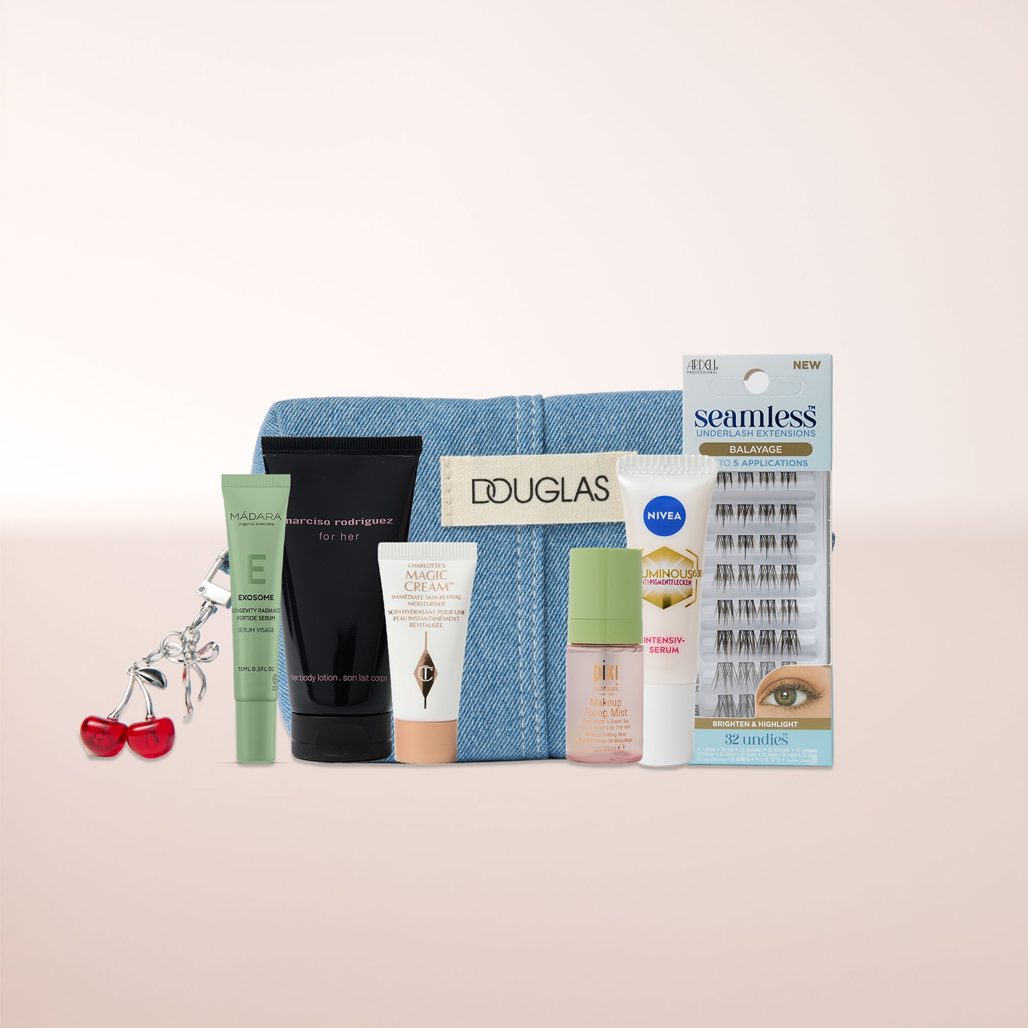 Eine Douglas-Denim-Tasche ist mit einer Auswahl an Schönheitsprodukten gefüllt, darunter Madara Exosome Serum, Narciso Rodriguez Body Lotion, Charlotte's Magic Cream, Pixi Makeup Fixing Mist, Nivea Luminous Serum und Ardell Seamless Underlash Extensions, ergänzt durch einen Kirsch-Schlüsselanhänger.