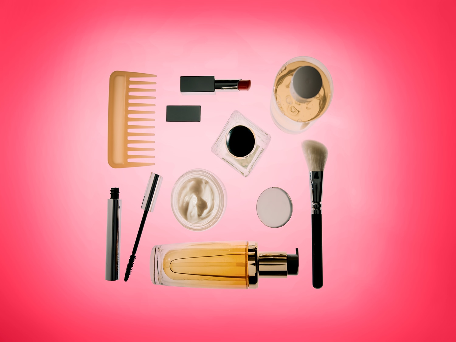 Een verzameling make-up en haarverzorgingsproducten, waaronder een kam, mascara, lippenstift, crèmes, parfum en een make-upkwast, allemaal netjes gerangschikt op een levendige roze achtergrond.