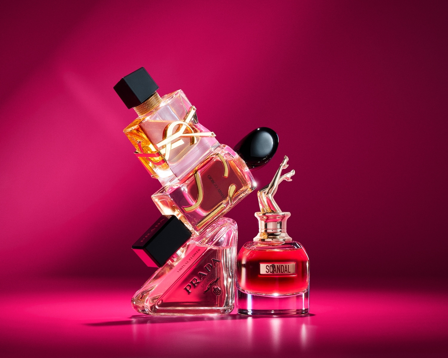 Een stijlvolle opstelling van verschillende luxe parfumflesjes op een levendige roze achtergrond, met iconische geuren van topmerken.